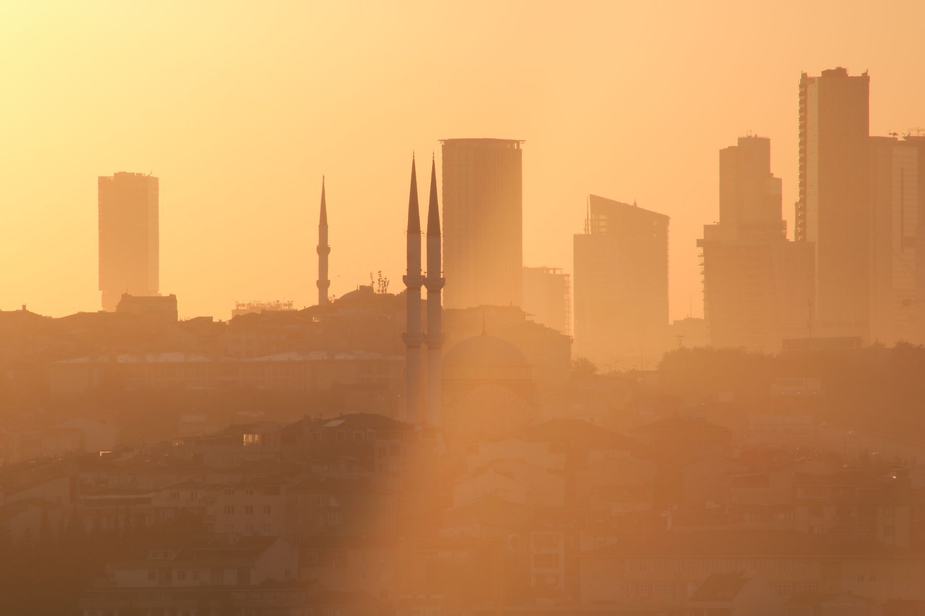 Sweeping view of Istanbul's historic skyline at sunset, with the Golden Horn and various mosques and minarets silhouetted against a vibrant sky.
