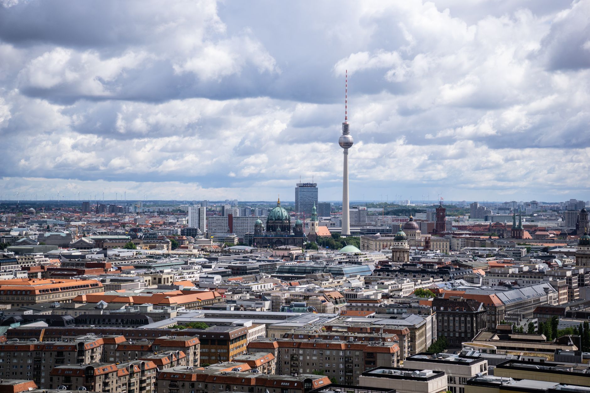A wide, sweeping view of historic Berlin, featuring the Brandenburg Gate at dawn with warm light, hinting at the city's deep historical layers.