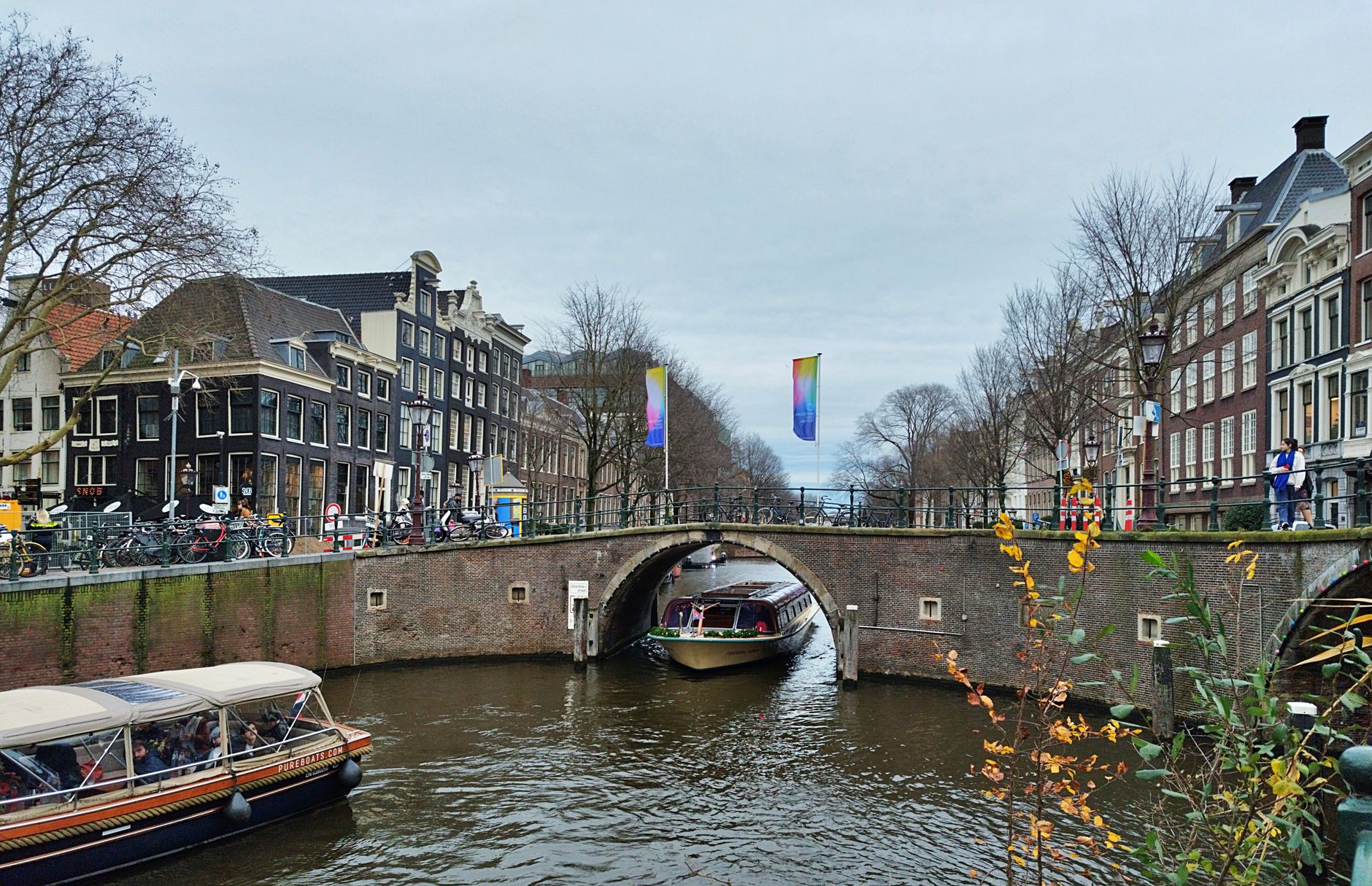 A quiet, narrow canal in Amsterdam, flanked by historic brick buildings, with a small boat gently moored, evoking a sense of discovery away from the main tourist paths.