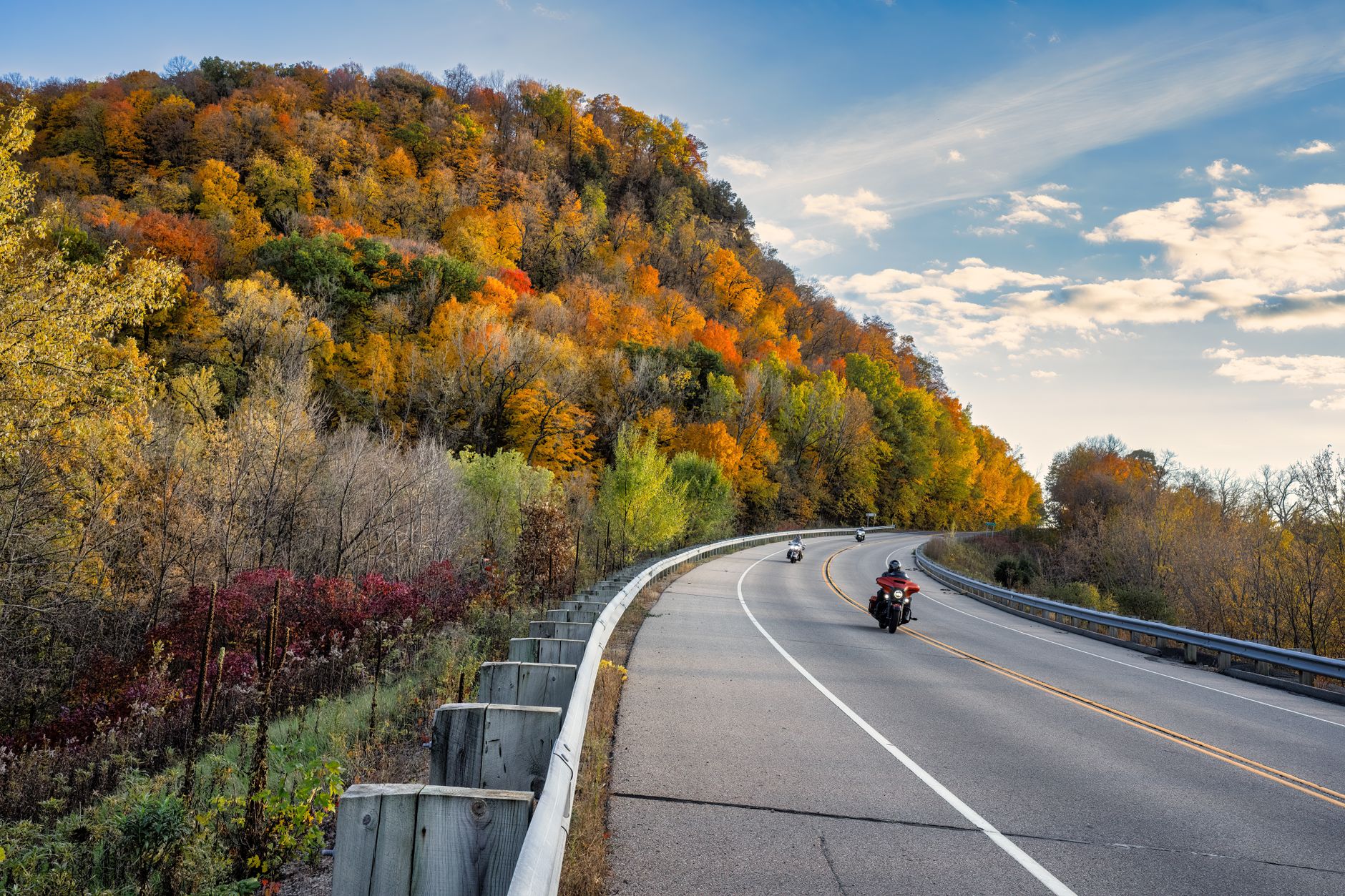 Sweeping aerial view of a winding road cutting through vibrant autumn forests in rural Ontario, hinting at the journey between Montreal and Niagara Falls.