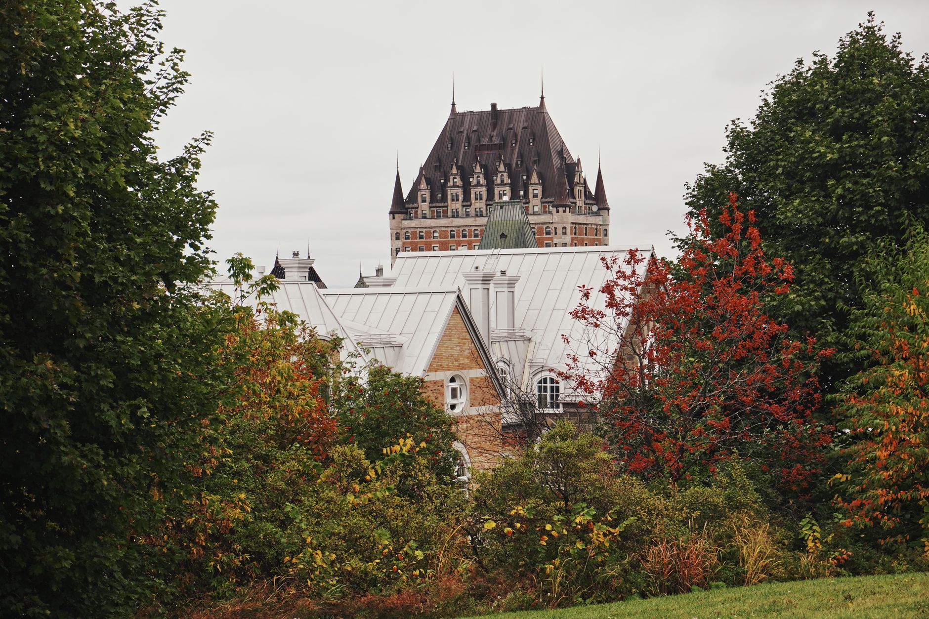 A sweeping view of a historic Canadian landscape, perhaps an old stone building nestled by a river under a dramatic sky, symbolizing the deep history and diverse cultures of the nation.