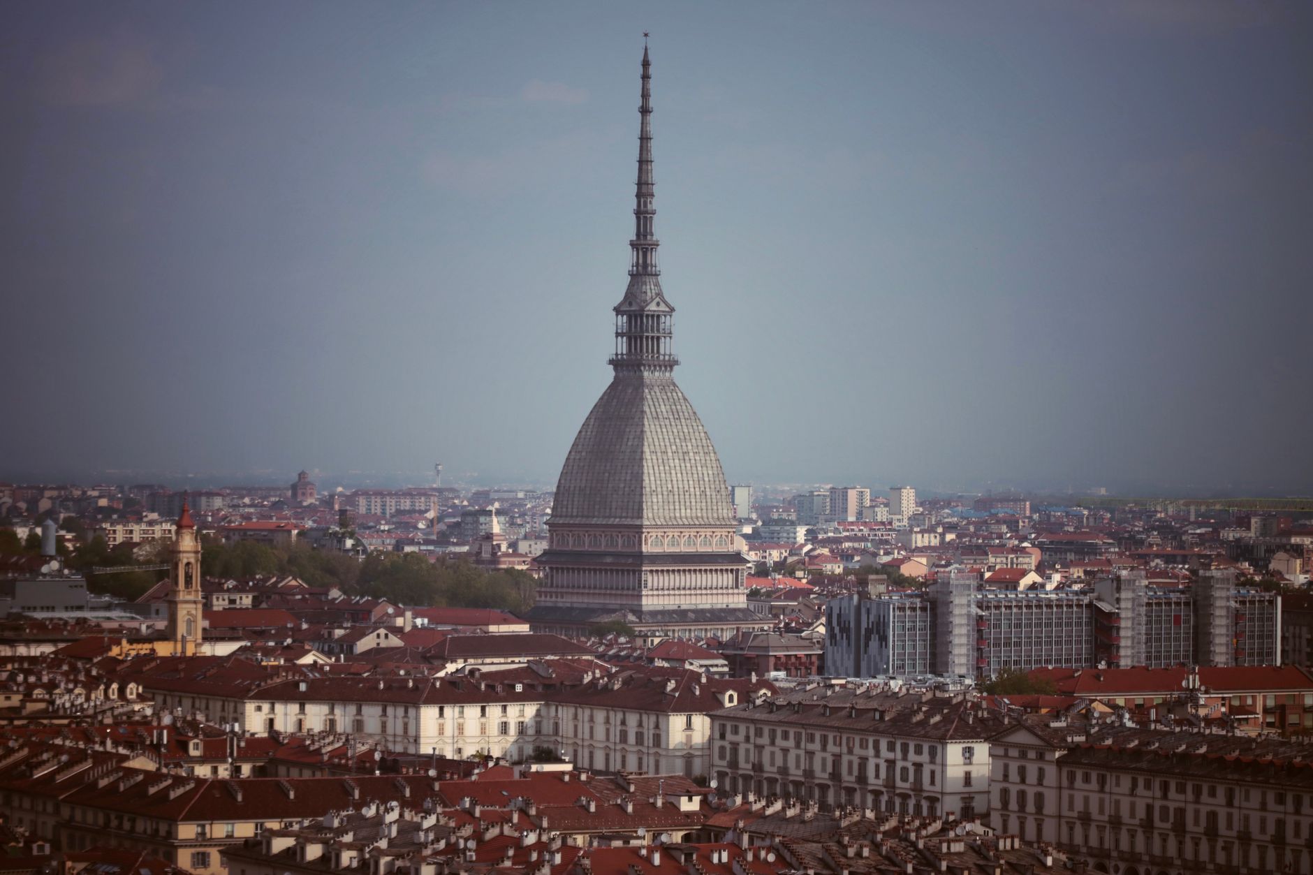 A panoramic view of Turin's historic city center with the Alps in the background, showing bustling streets and elegant Baroque architecture.