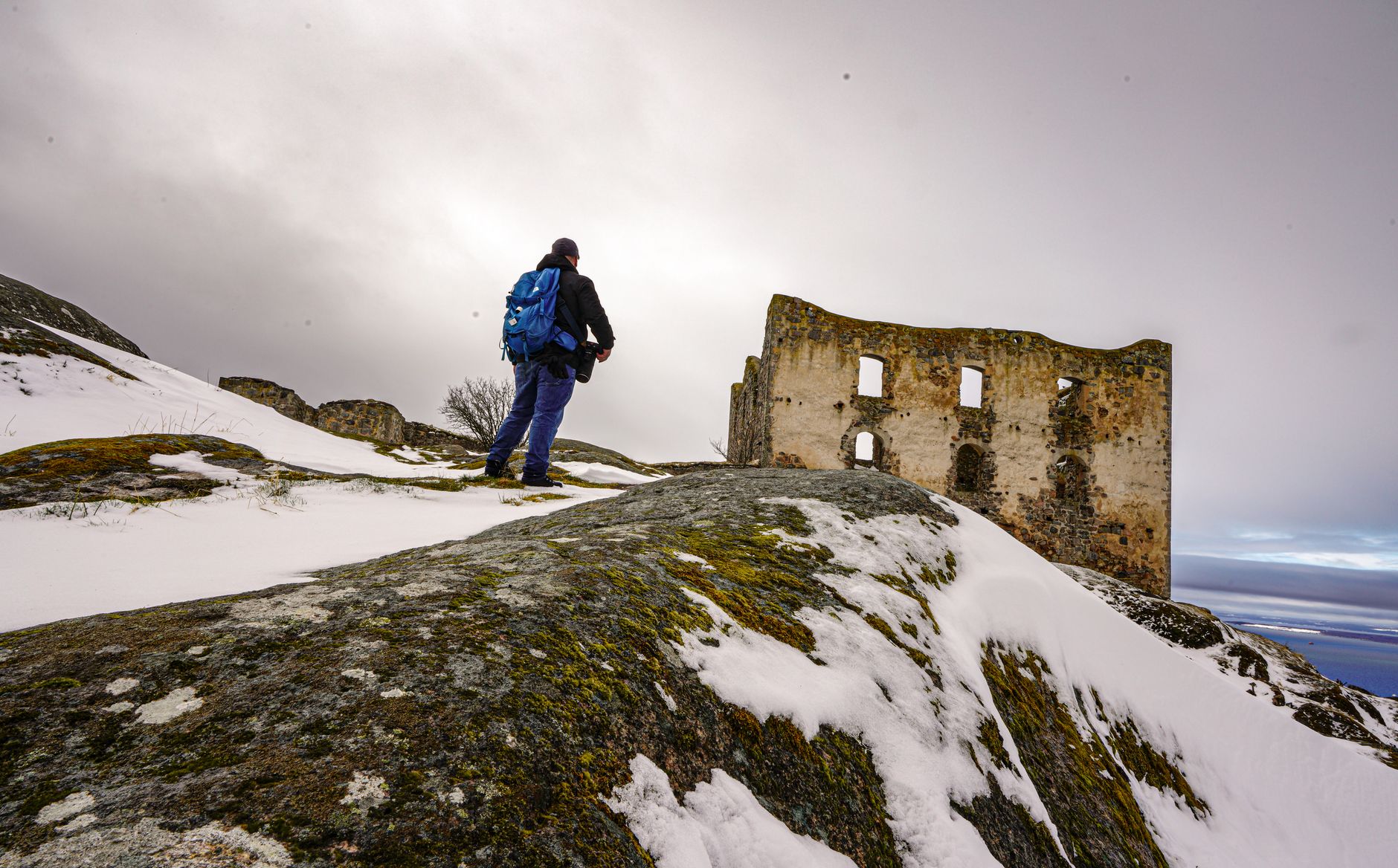 A lone traveler stands on a rocky outcrop overlooking a vast, misty valley, evoking a sense of discovery and awe.