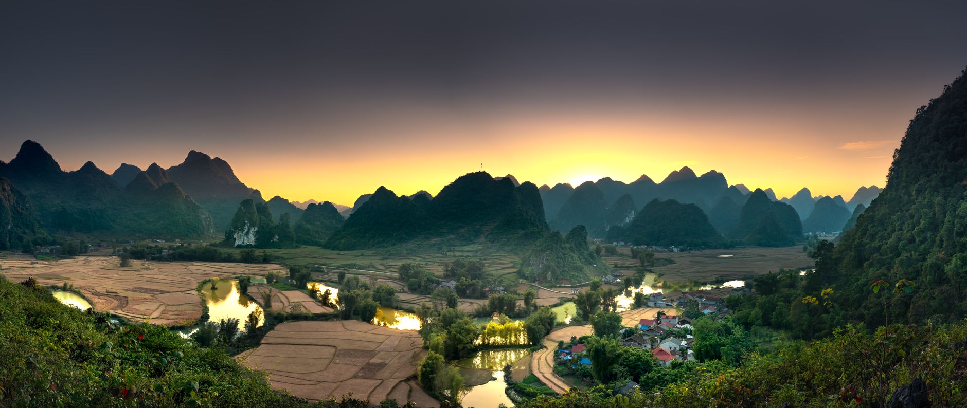 A serene, wide-angle view of an ancient Asian temple complex shrouded in morning mist, with verdant mountains in the background, hinting at cultural depth and natural beauty.