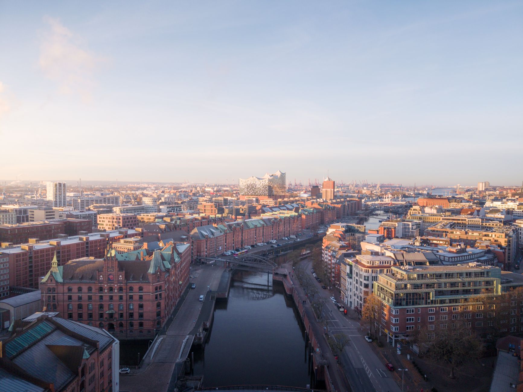Panoramic view of Hamburg's historic Speicherstadt canals and modern architecture under a vibrant sky, hinting at the city's hidden depths.