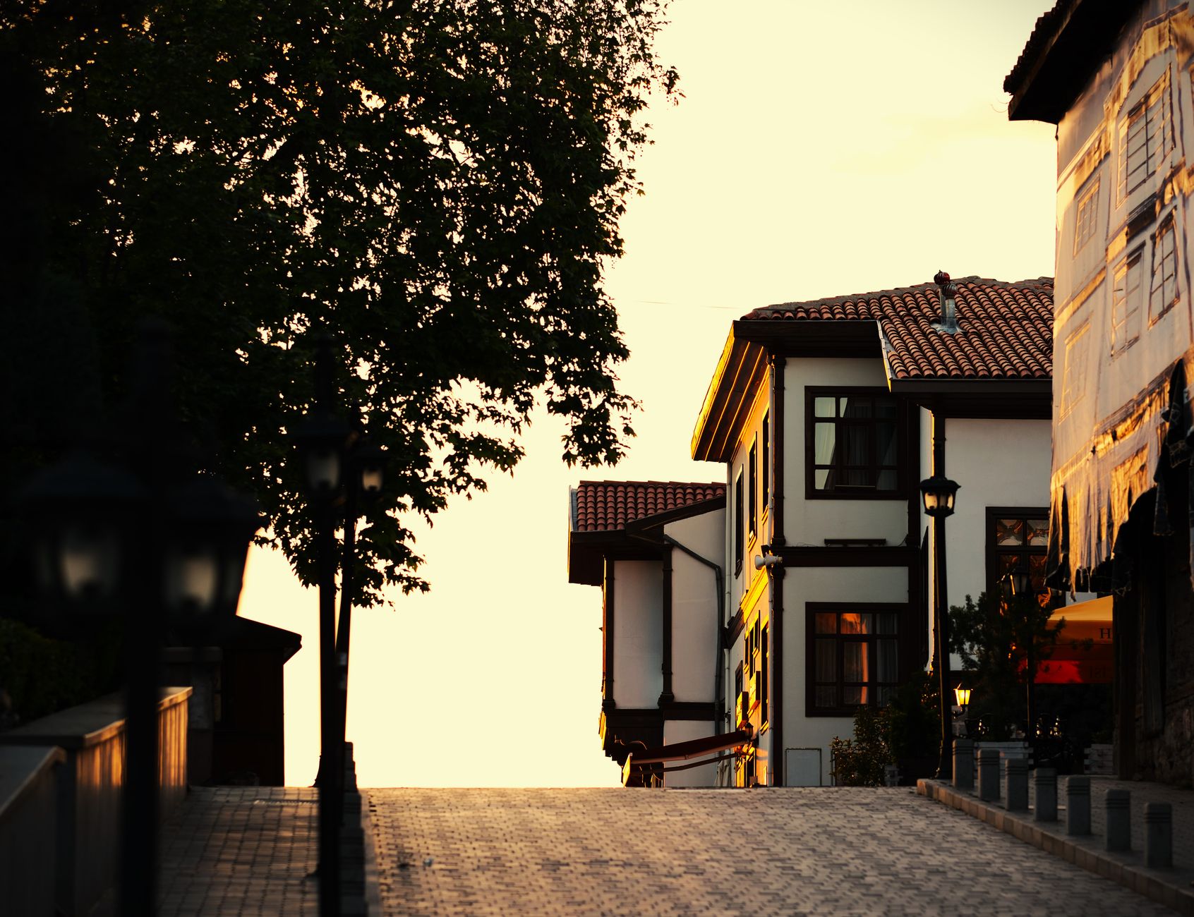 A quiet, sun-dappled alleyway in Solvang, California, revealing intricate Danish-style architecture beyond the main tourist thoroughfares.