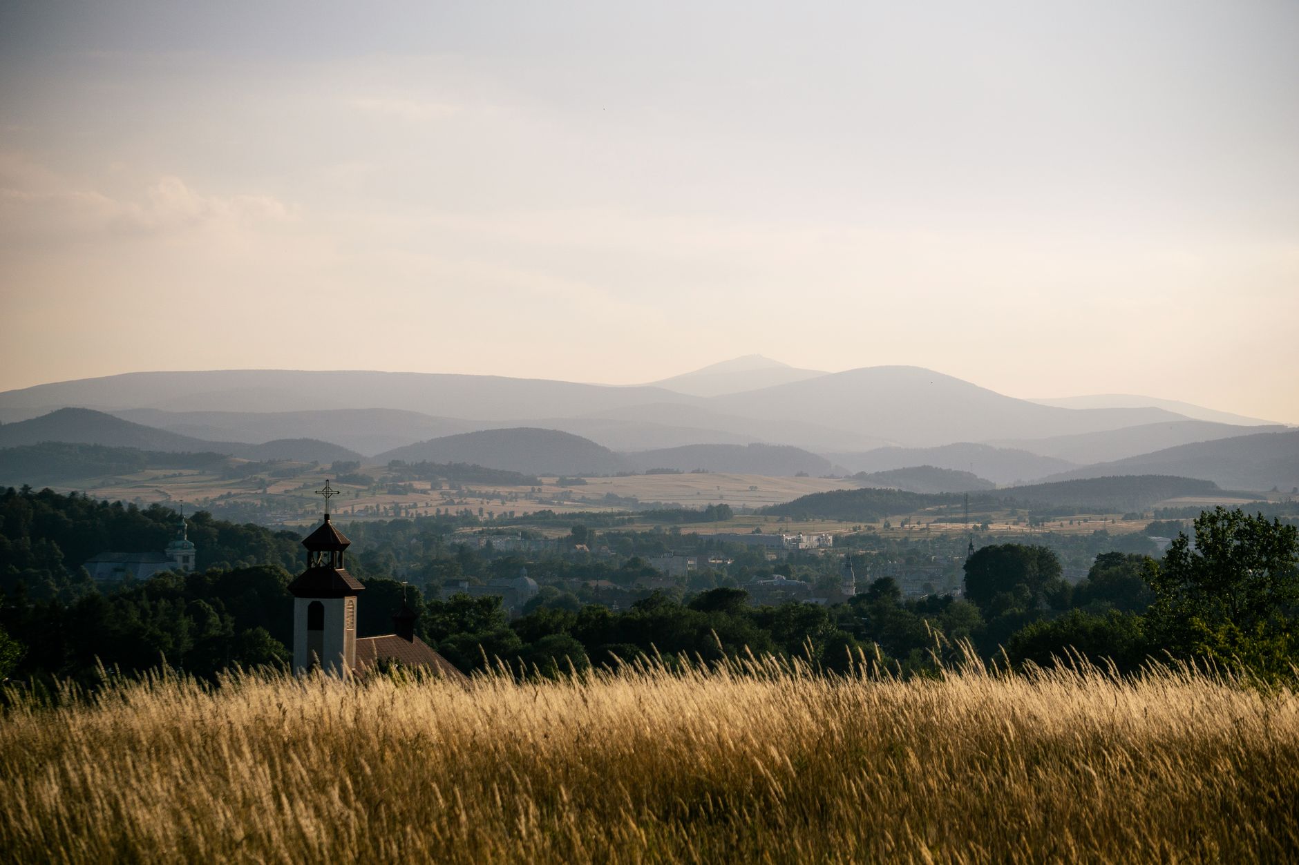 A sweeping panoramic view of the Polish countryside with a medieval castle perched on a distant hill, under a dramatic sky, evoking a sense of discovery and history.