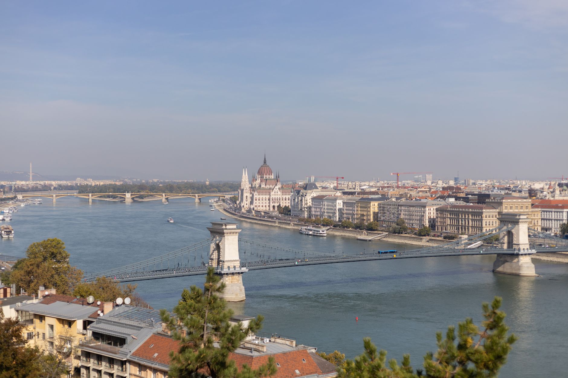 A sweeping, atmospheric view of Budapest, showcasing a mix of historical and residential architecture along the Danube, hinting at hidden stories within the city.
