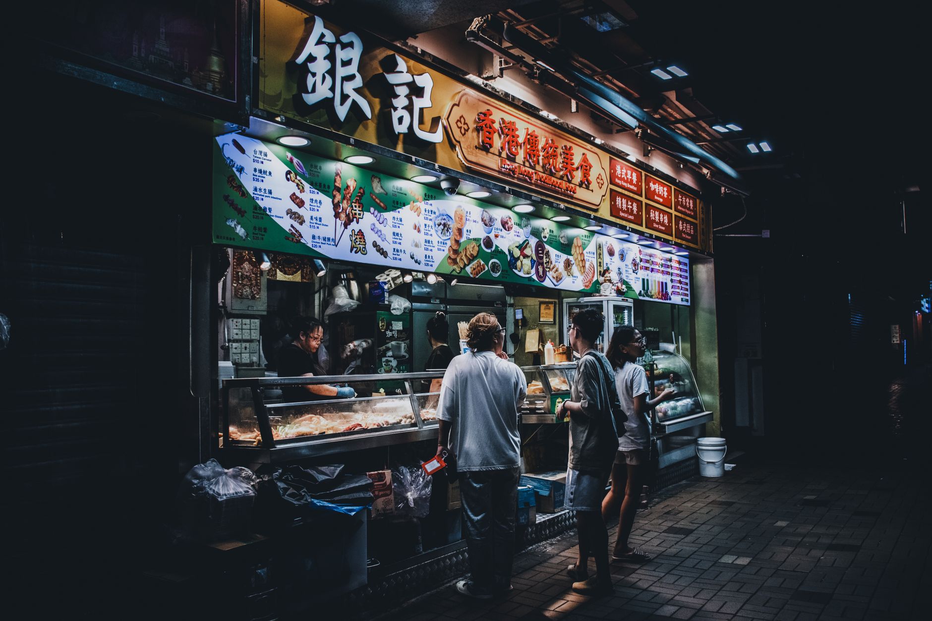 A vibrant, bustling street food market with a mix of local vendors and curious travelers trying different dishes.