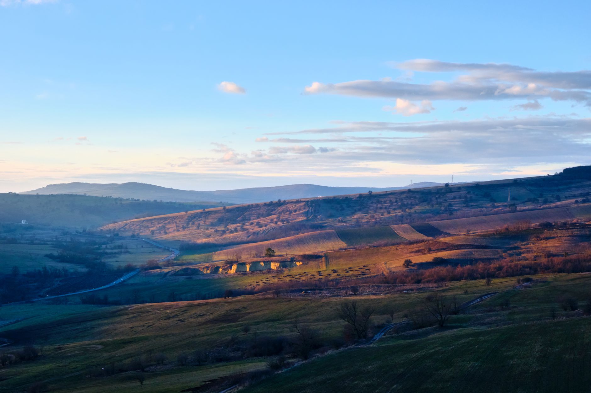 A dramatic, sweeping landscape photograph showcasing an ancient, remote village perched on a cliff edge at sunset, evoking a sense of mystery and discovery.