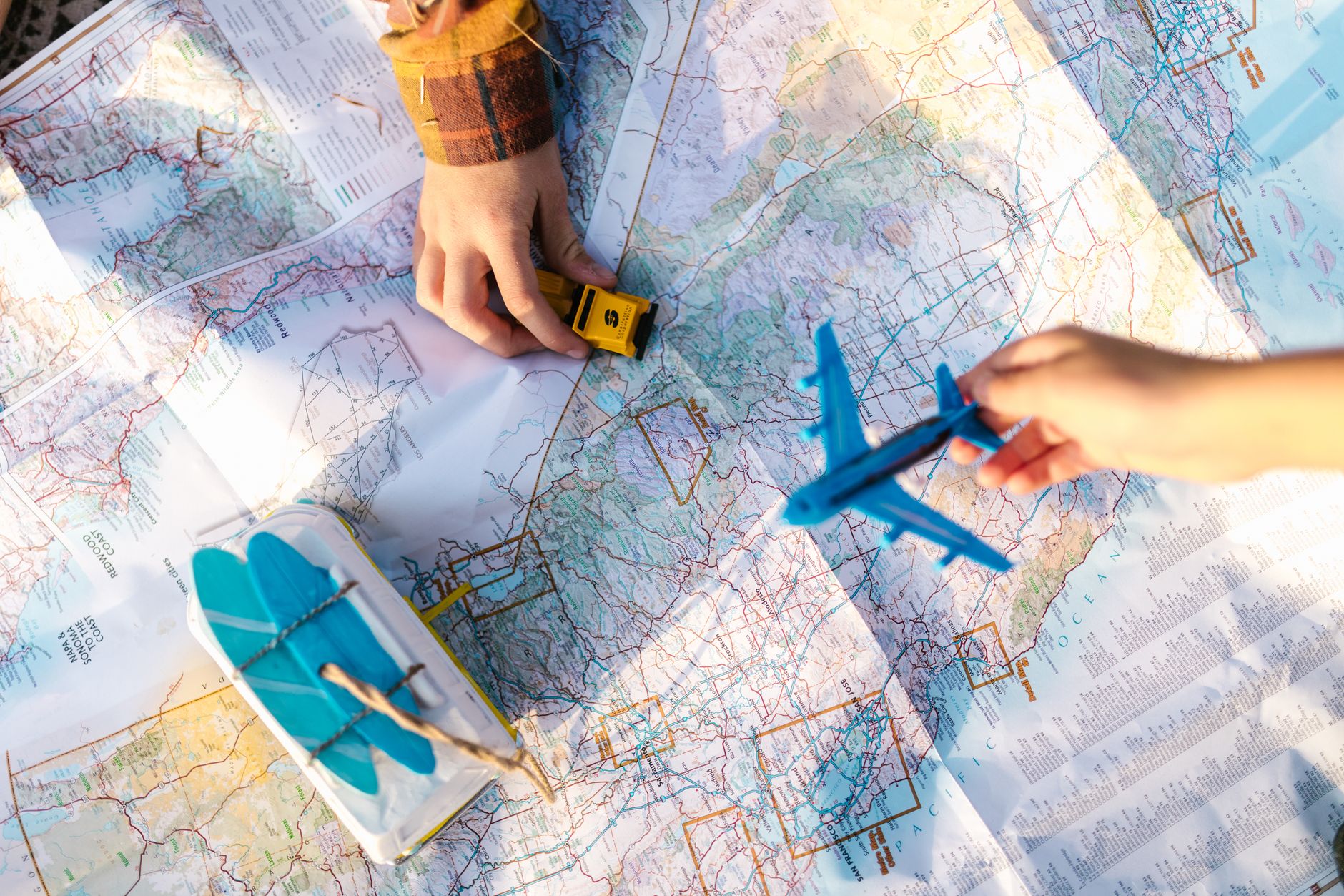A retro photo of a family gathered around a large paper map, pointing at destinations, symbolizing traditional vacation planning before digital tools.