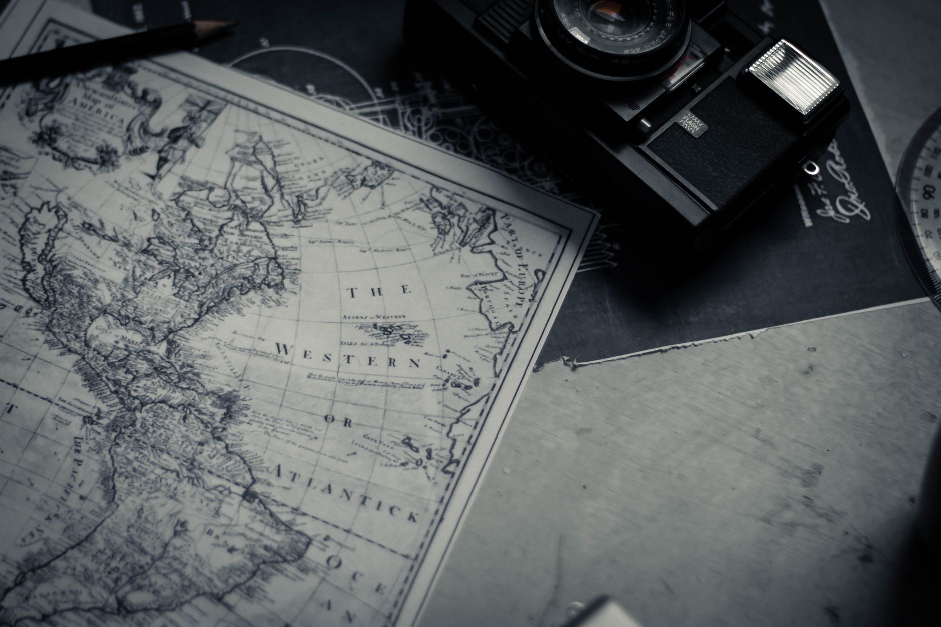 A family gathered around a large paper map spread on a table, pointing at destinations with guidebooks and travel brochures nearby, evoking pre-internet vacation planning.