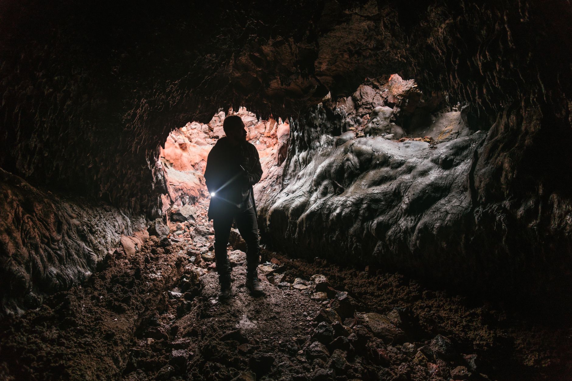 A beam of light piercing through the darkness of a vast underground cave, illuminating intricate rock formations and a narrow path.