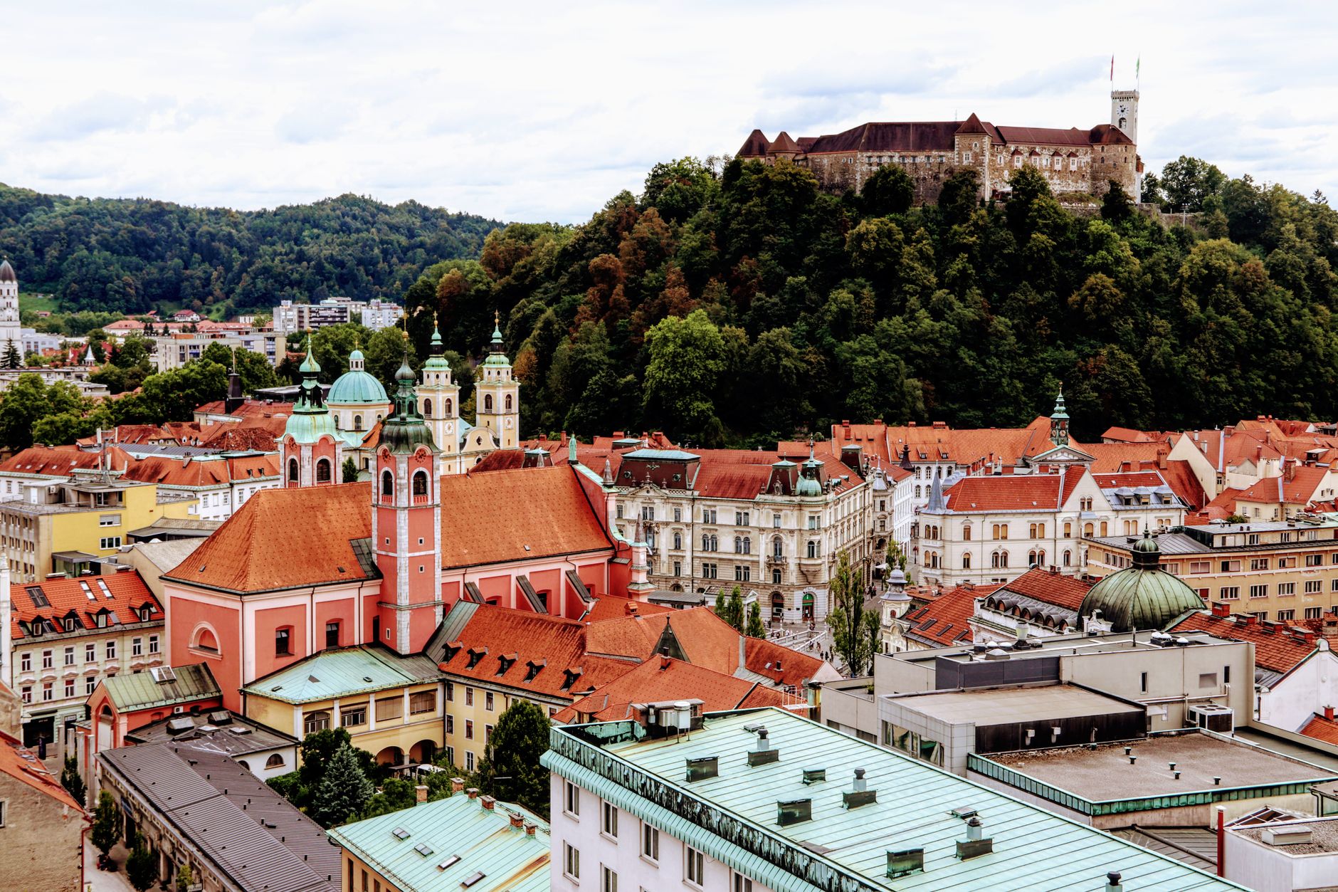 Sweeping aerial view of Ljubljana, Slovenia, at sunset, showing the old town, Ljubljanica river, and the castle on the hill.