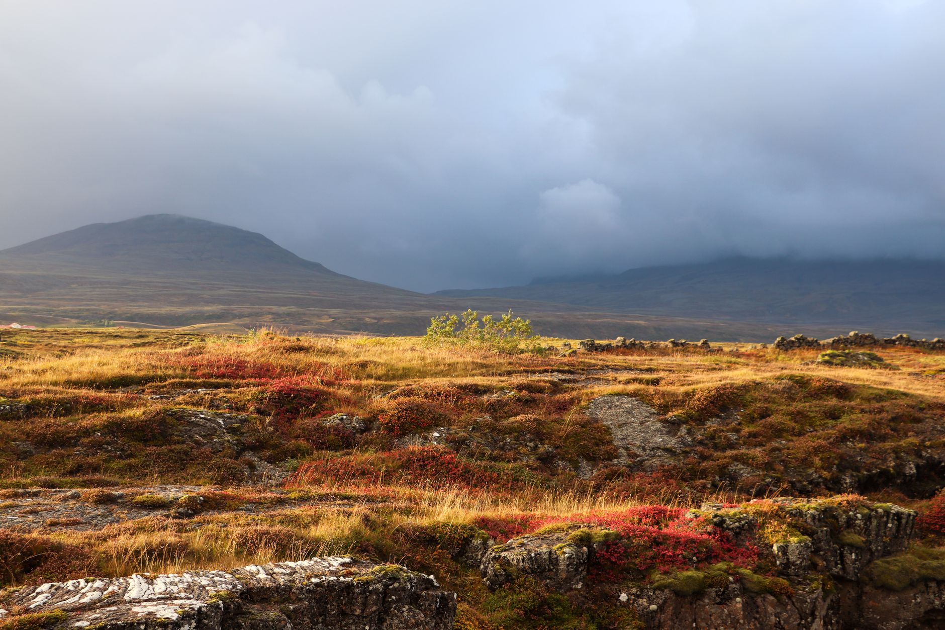 A lone figure standing on a vast, empty road stretching towards distant mountains under a dramatic sky, symbolizing budget travel and exploration.