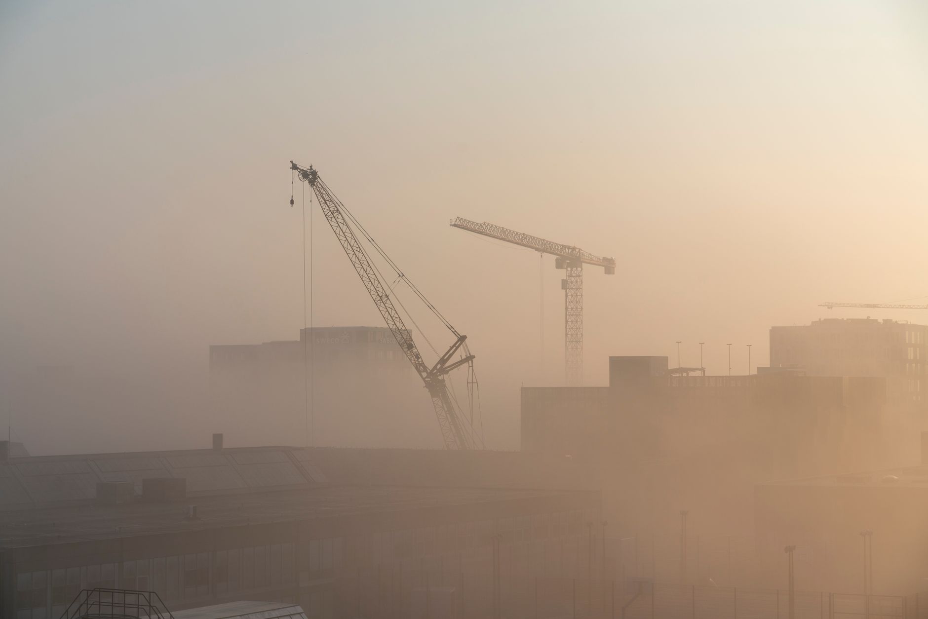 Panoramic view of Copenhagen at dawn, showing historic buildings, canals, and a blend of traditional and modern architecture under a soft light.