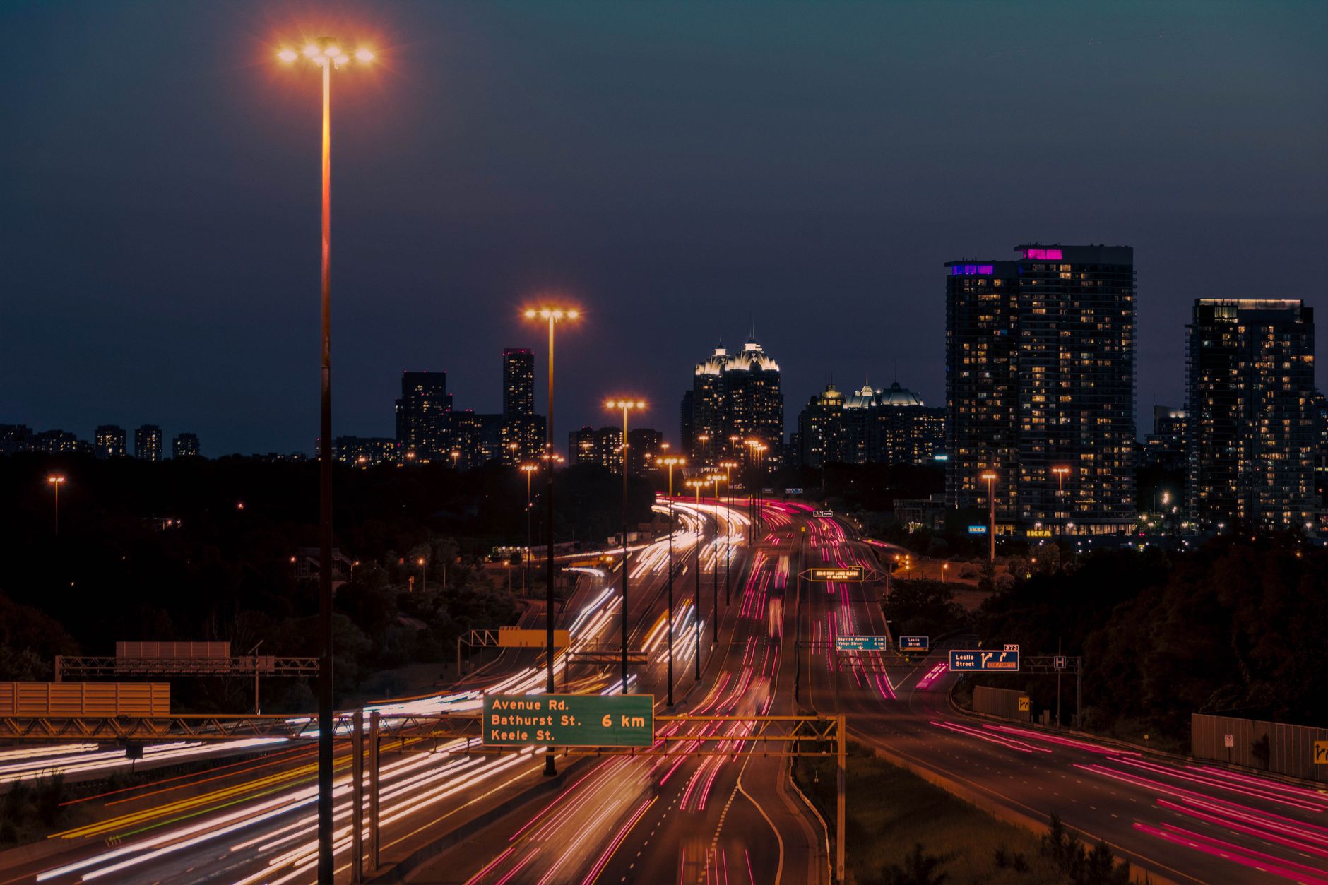 Empty stretch of highway under a starry sky, with distant car lights, suggesting a long-distance drive between Toronto and Montreal.
