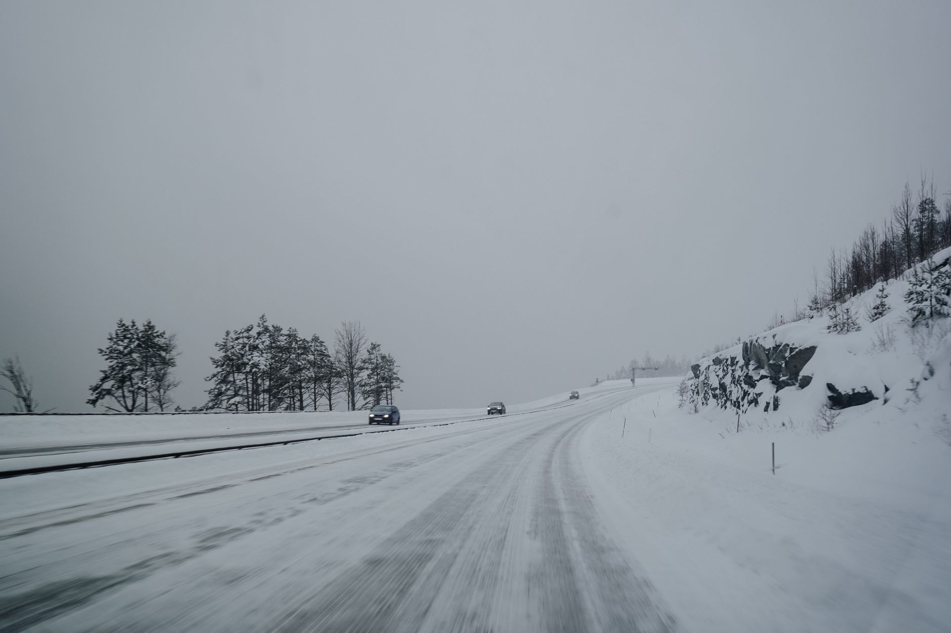 A long, empty stretch of a snow-covered highway winding through a rural landscape between Montreal and Ottawa on a crisp winter morning, with distant trees dusted in white.