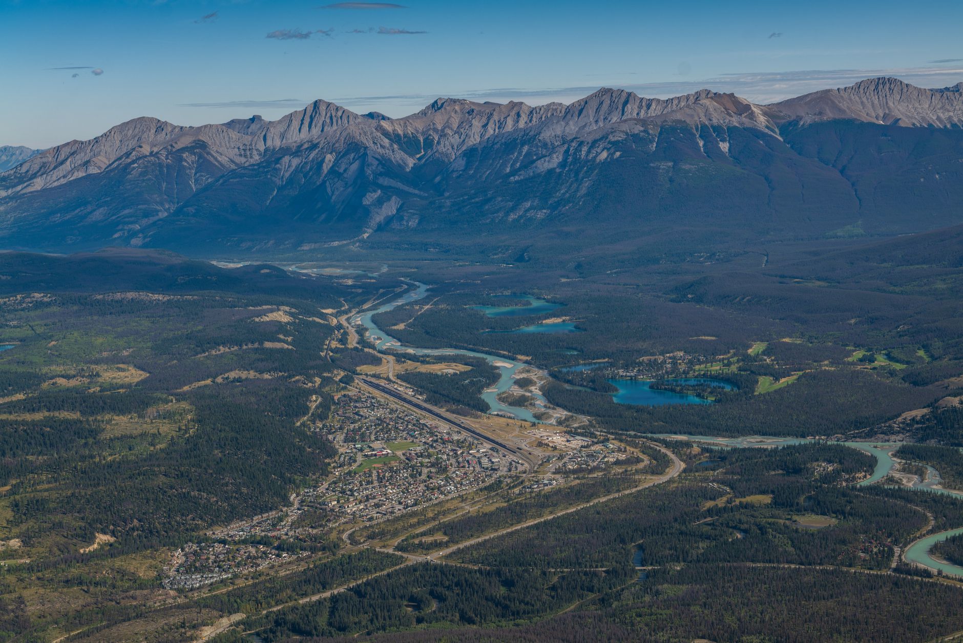 Aerial view of a charming Canadian town nestled along a wide river, with historical buildings and a clear horizon, symbolizing cross-border exploration.