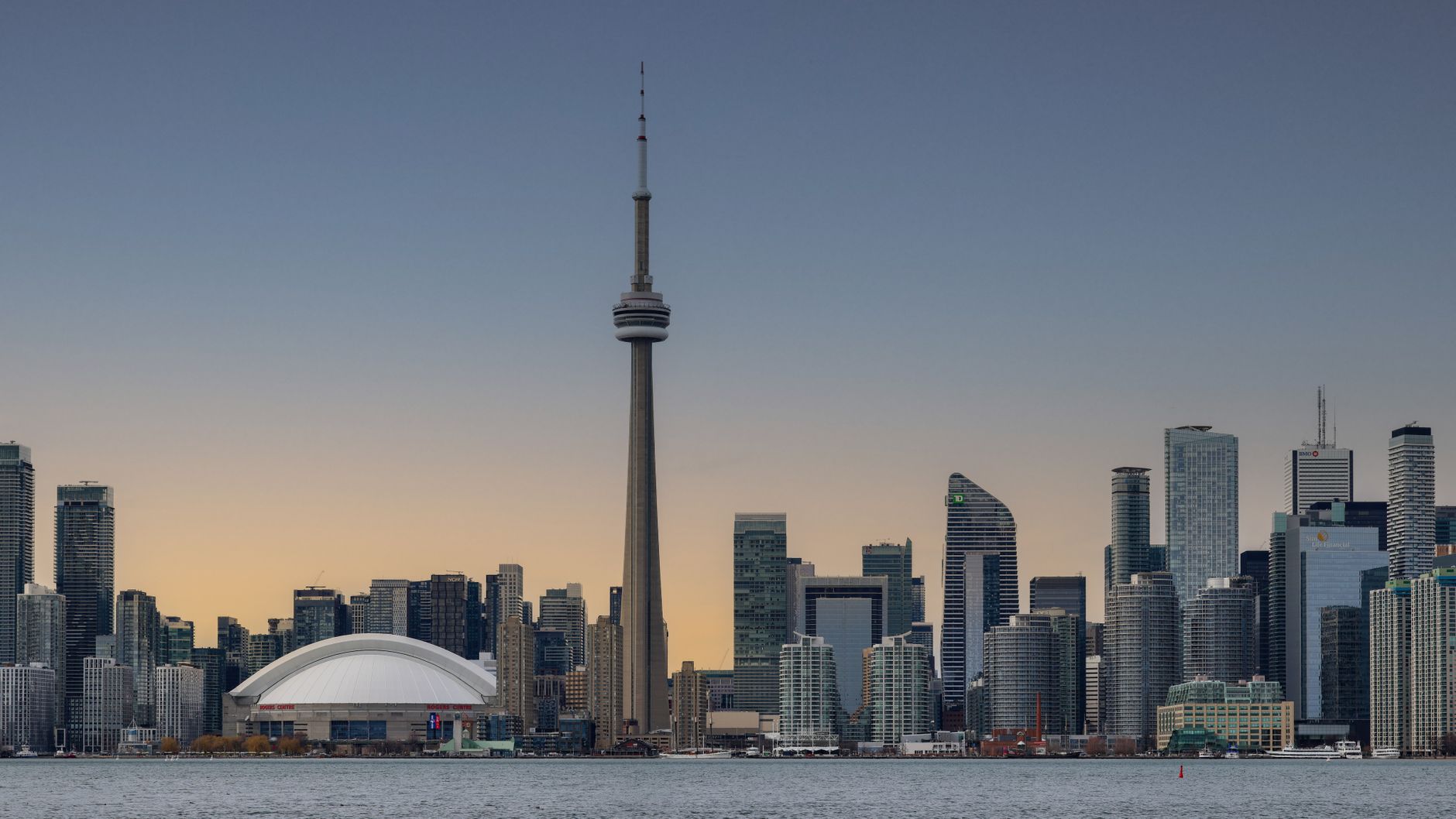 Sweeping view of Toronto's diverse cityscape and waterfront at sunset, hinting at hidden stories within its neighborhoods.