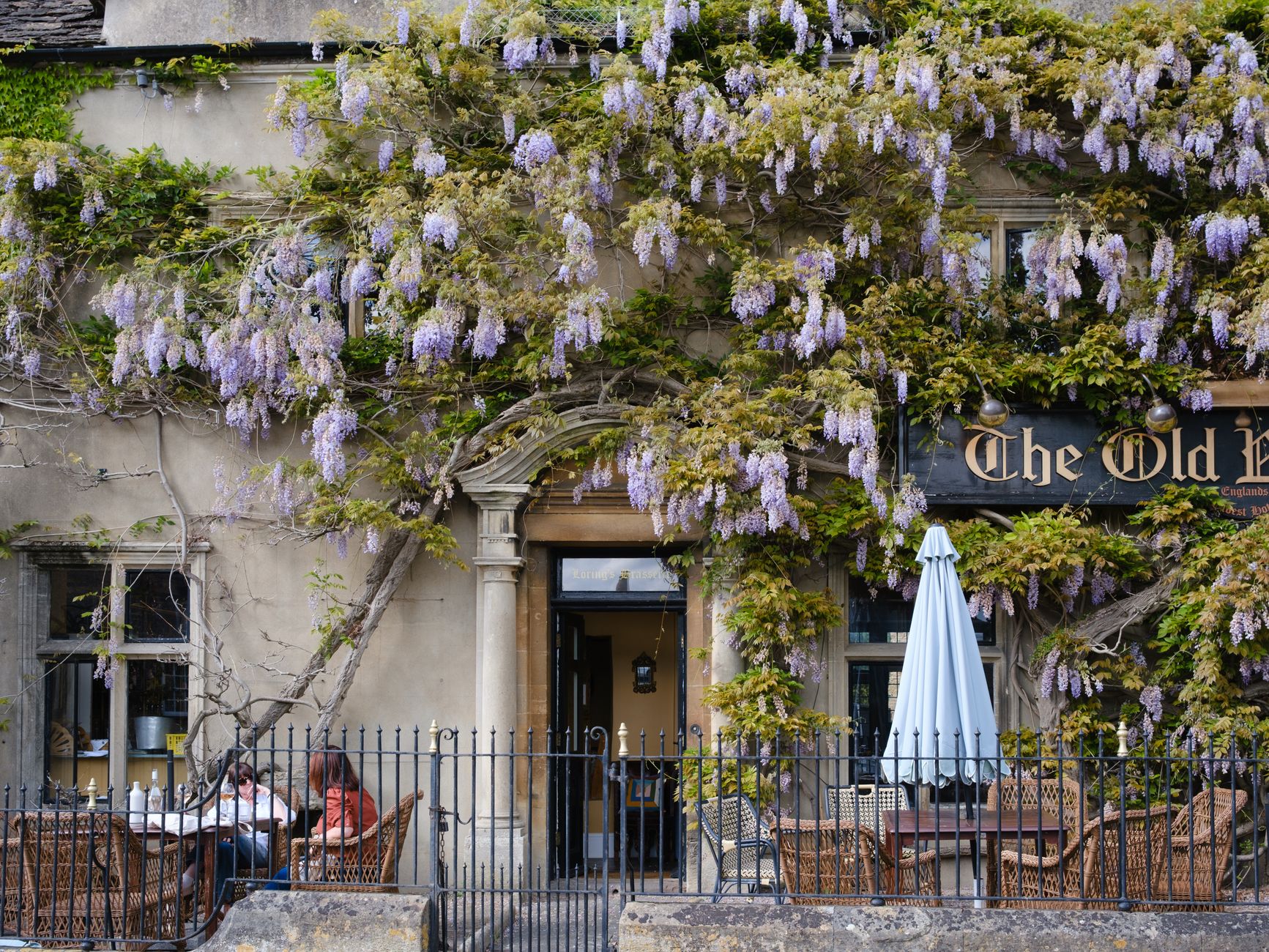 A charming, historic British pub with a welcoming entrance, set in a picturesque village, suggesting a place where families might gather.