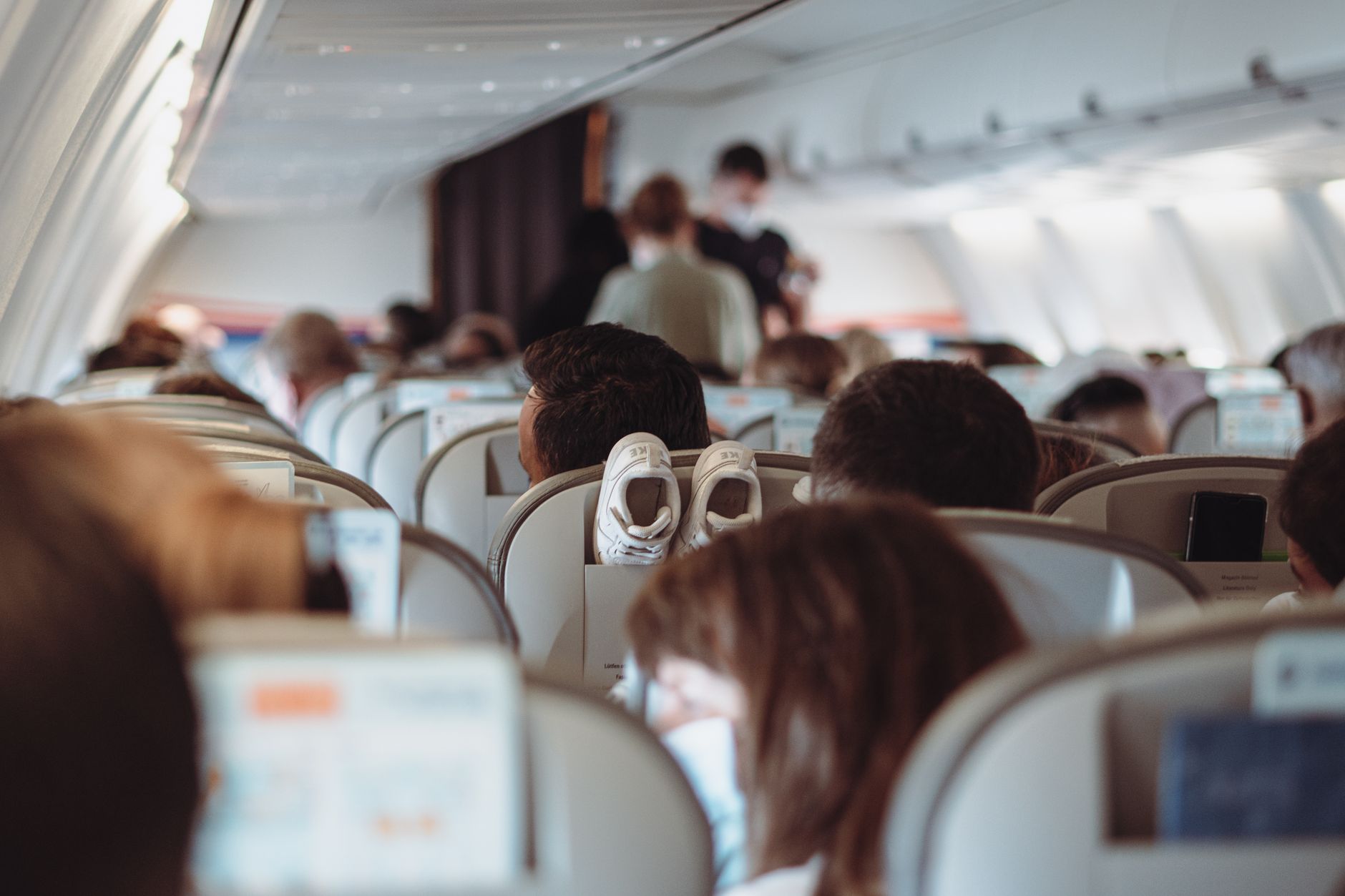 A traveler looking out an airplane window at a vast, diverse landscape, symbolizing escape and discovery amidst travel challenges.