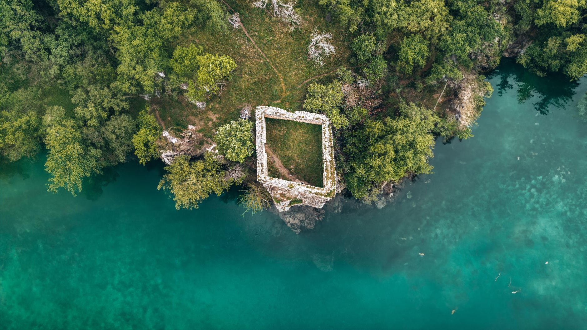 A sweeping landscape view of an ancient, unknown structure nestled in a misty valley, evoking mystery and untold stories.