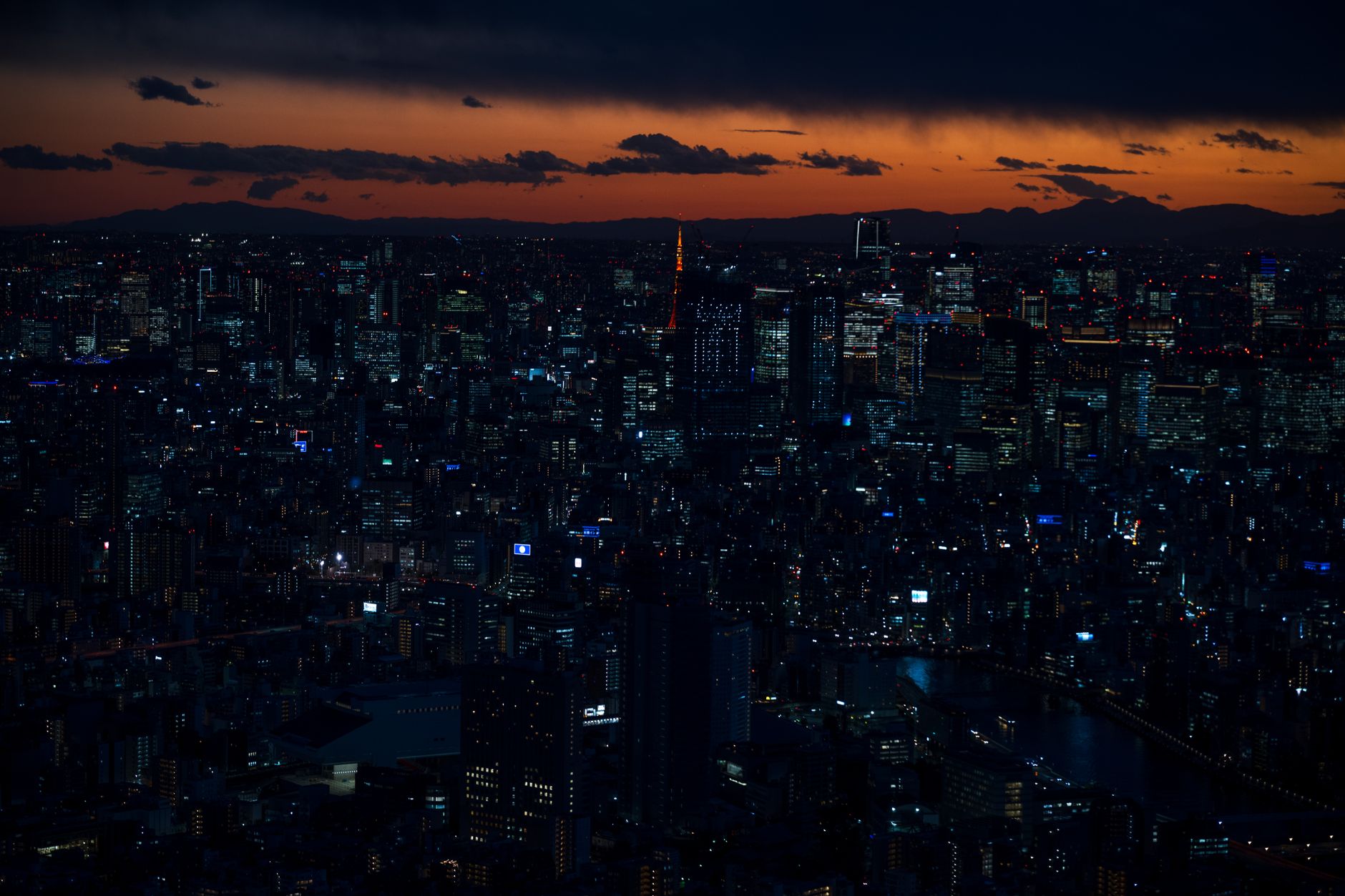 A panoramic view of Tokyo's diverse skyline at sunset, blending modern skyscrapers with glimpses of traditional rooftops and bustling streets.