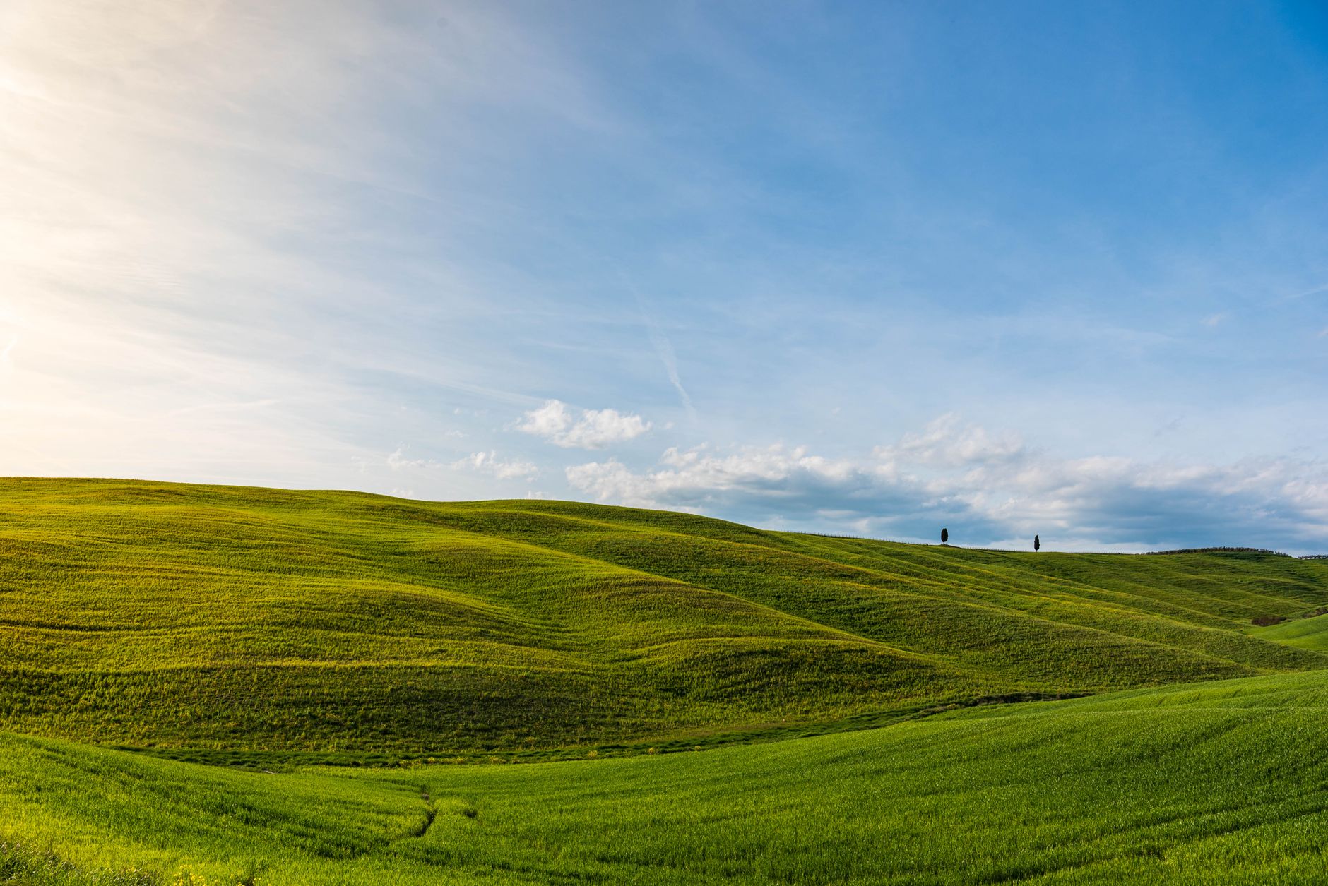 Sweeping view of a picturesque, lesser-known Italian village nestled in rolling hills at sunset, hinting at hidden stories.