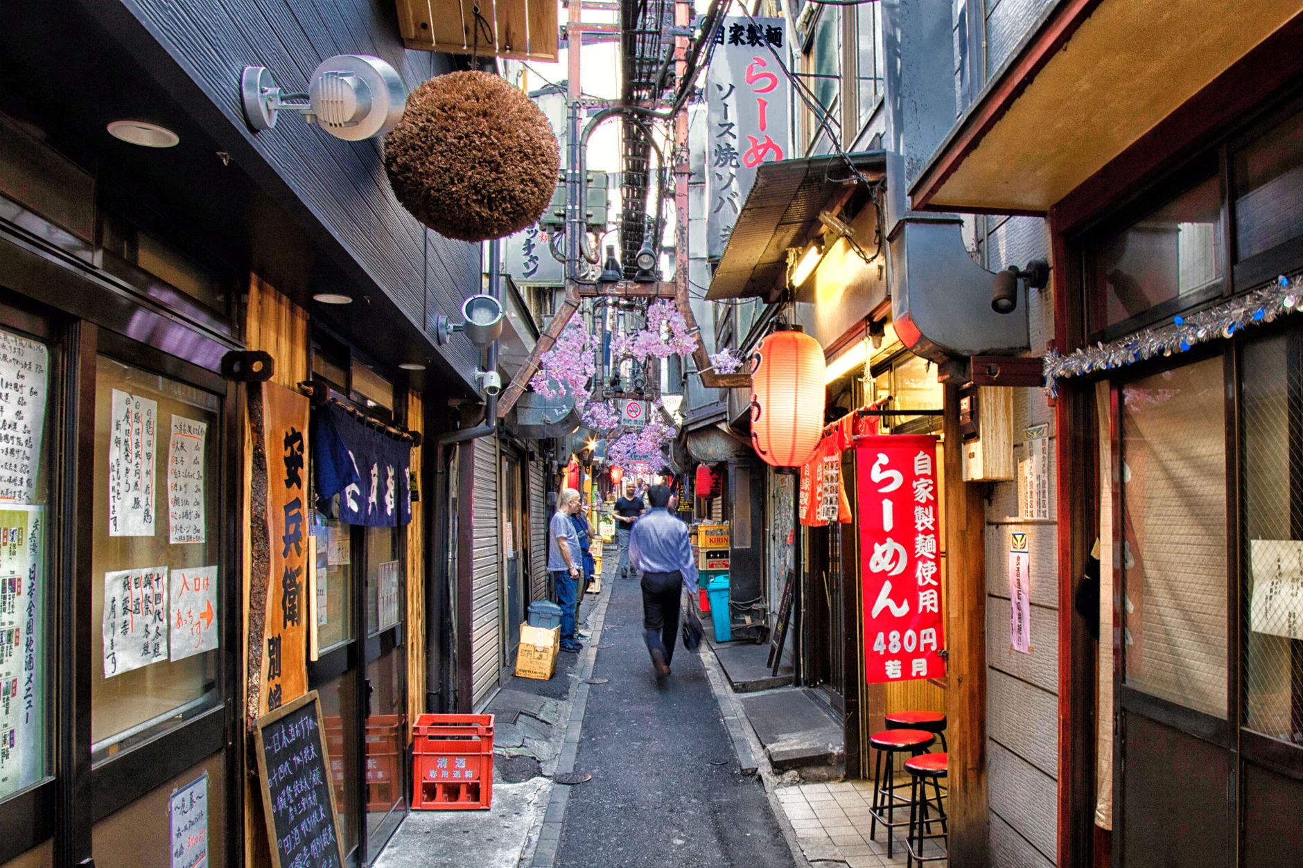 A quiet, narrow alley in an older Tokyo neighborhood, with traditional wooden buildings and soft lanterns, hinting at hidden stories.