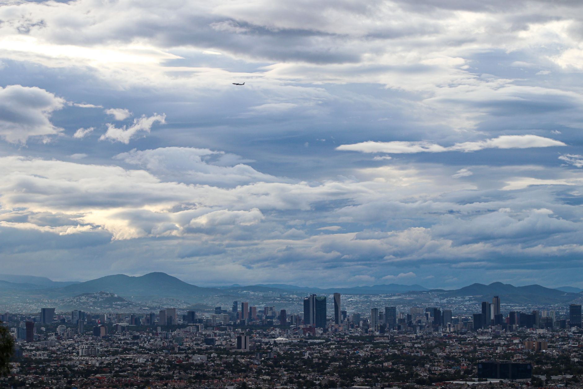 Sweeping panoramic view of Mexico City, showcasing a blend of historic colonial architecture, modern skyscrapers, and the vibrant life on its streets at sunset.