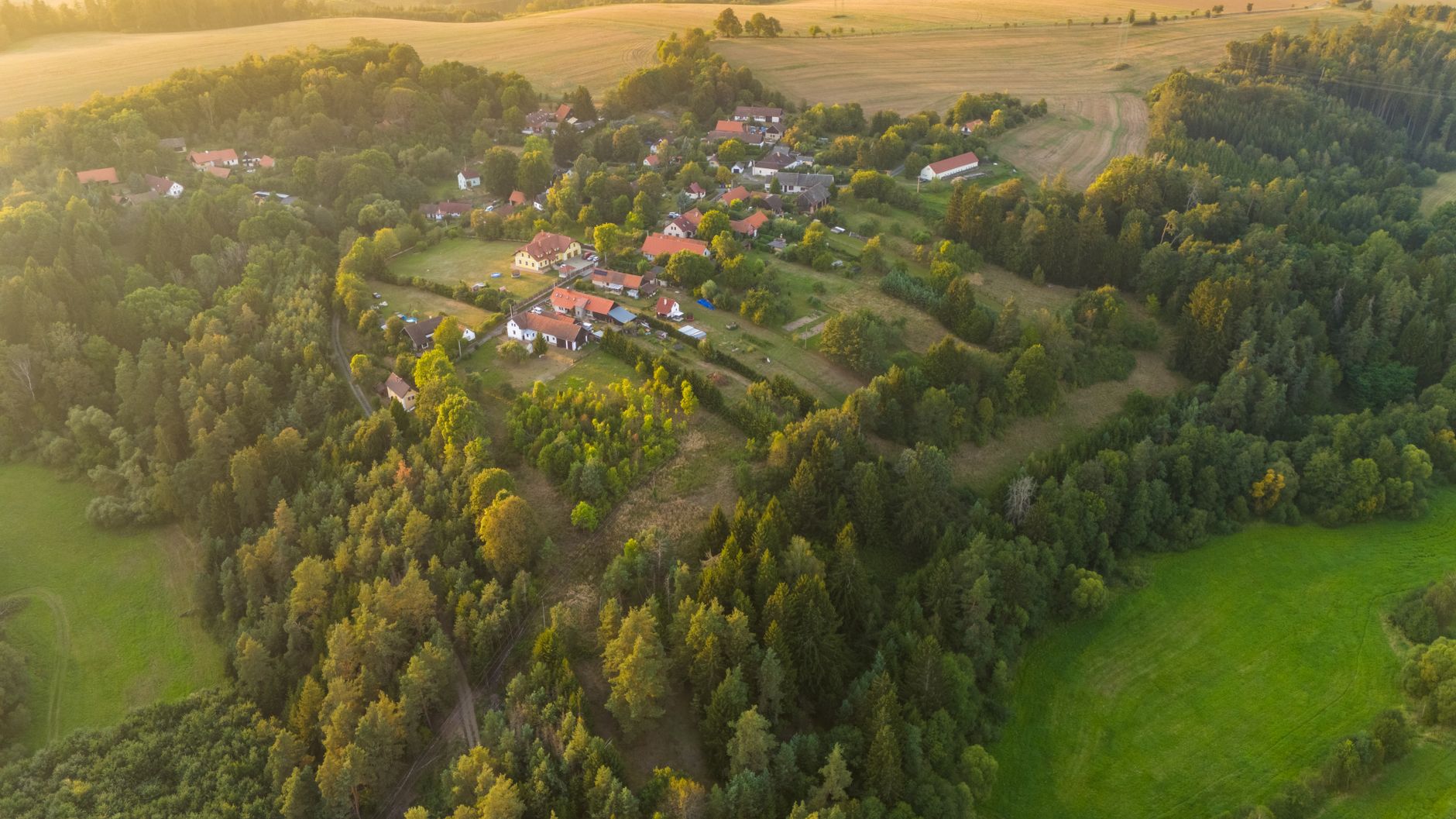 Sweeping panoramic view of the Bohemian countryside with rolling green hills, a distant castle, and clear summer sky.