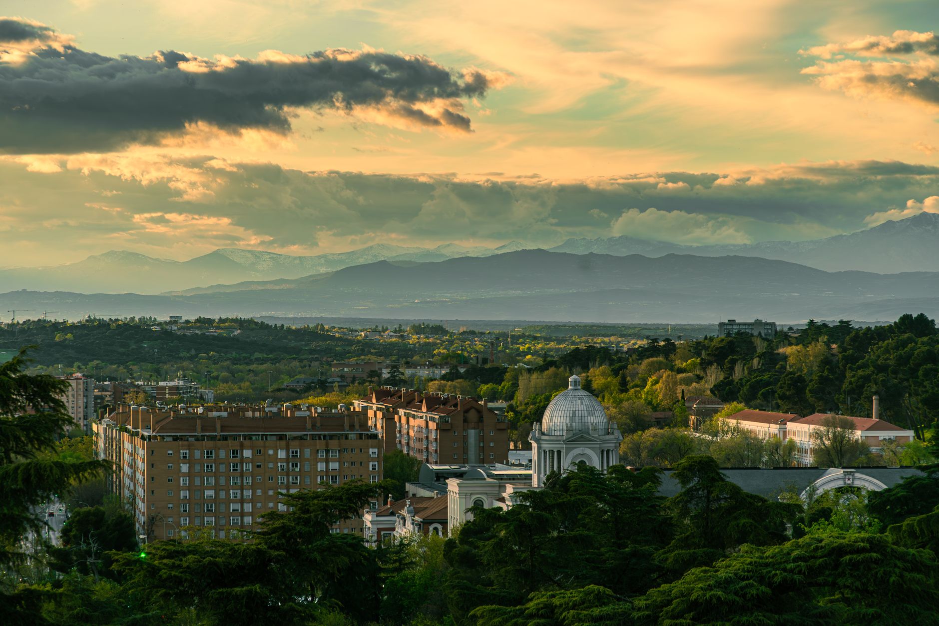 Sweeping view of Madrid's historic skyline at sunset, with rooftops and iconic landmarks visible, bathed in warm light.