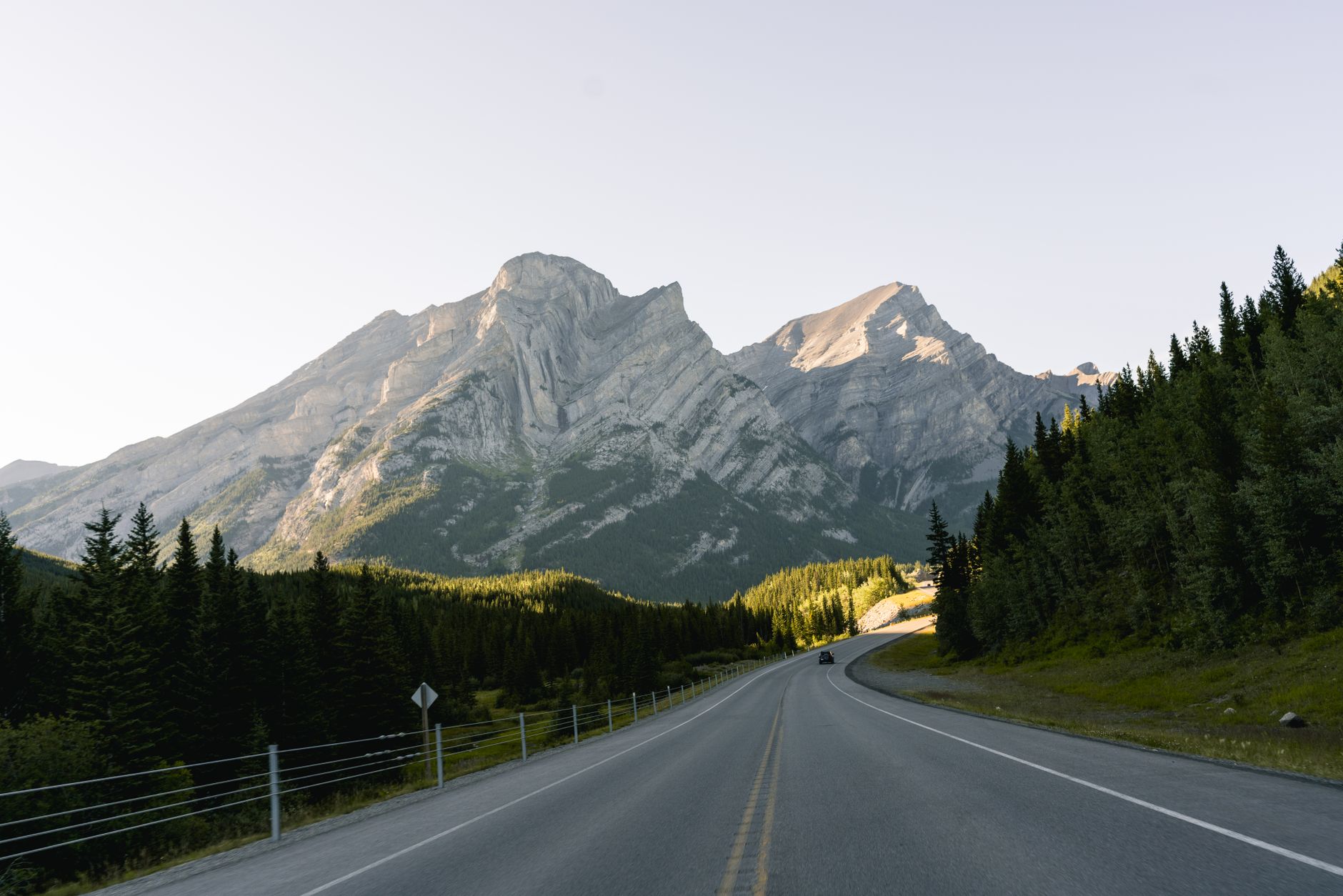 A scenic, winding road cutting through a vast Canadian landscape under a wide-open sky, symbolizing a long journey across the country.