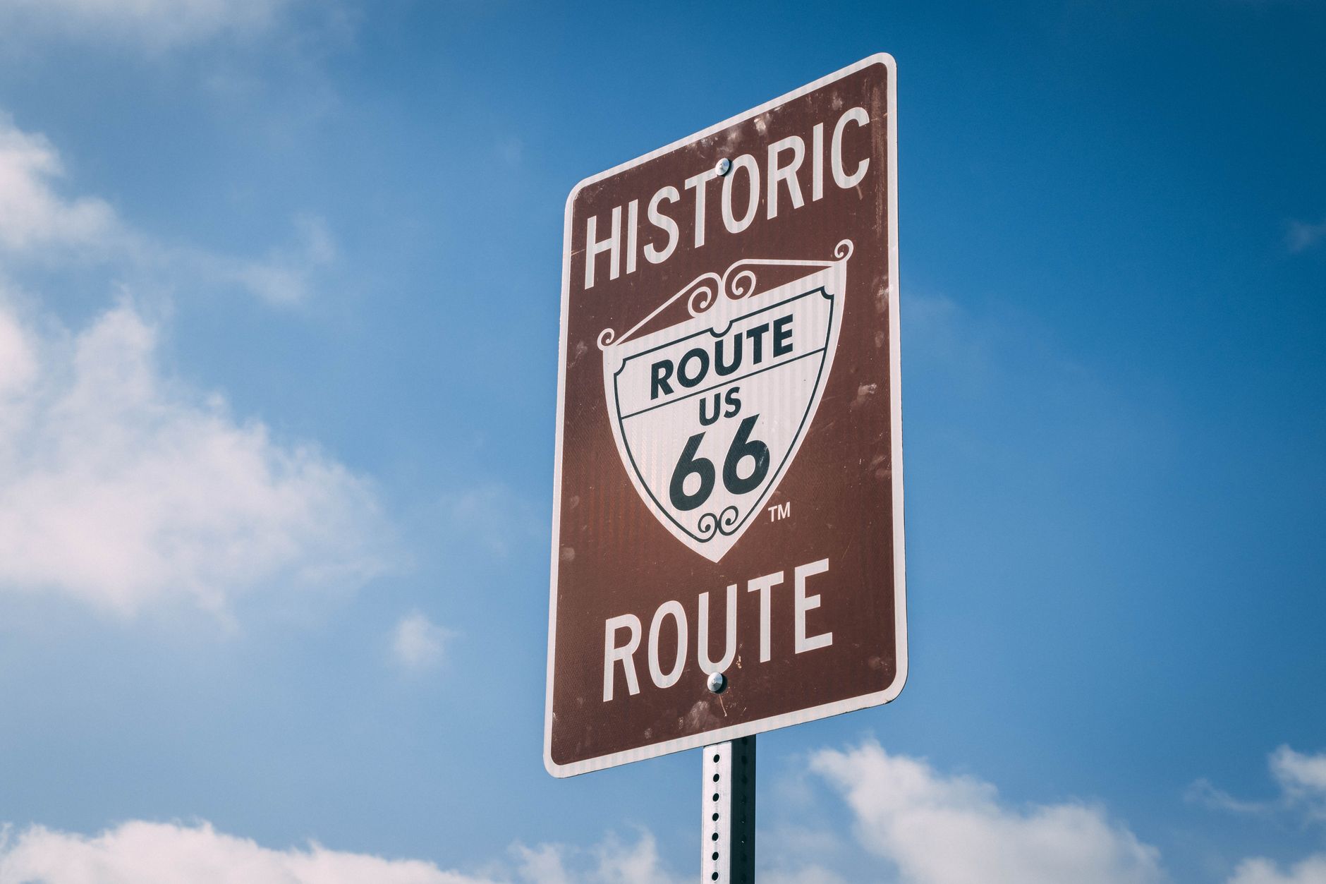 A winding road cuts through a vast, remote American landscape at sunset, hinting at hidden discoveries.