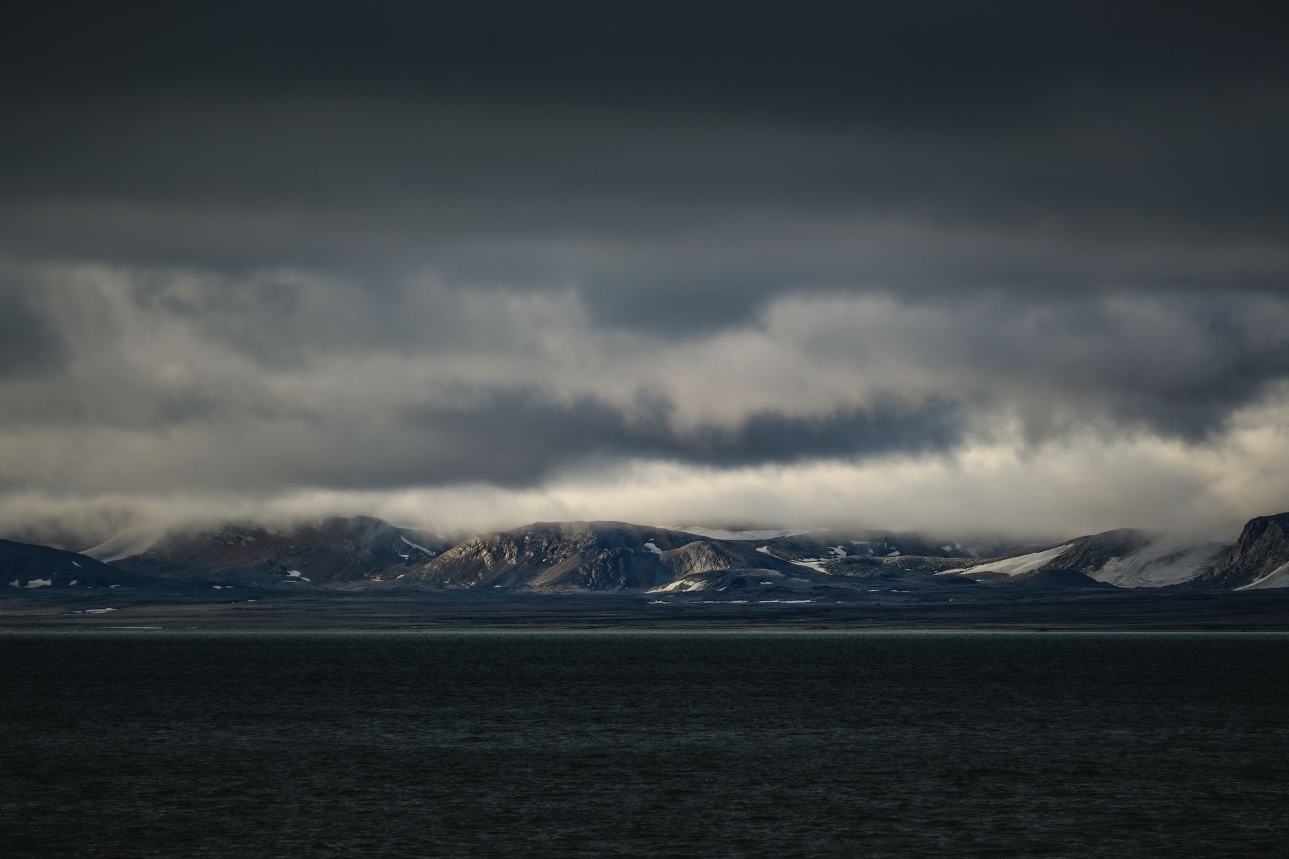 A sweeping panoramic view of a dramatic, remote landscape, perhaps a volcanic island or a vast desert, suggesting a journey to lesser-known destinations.