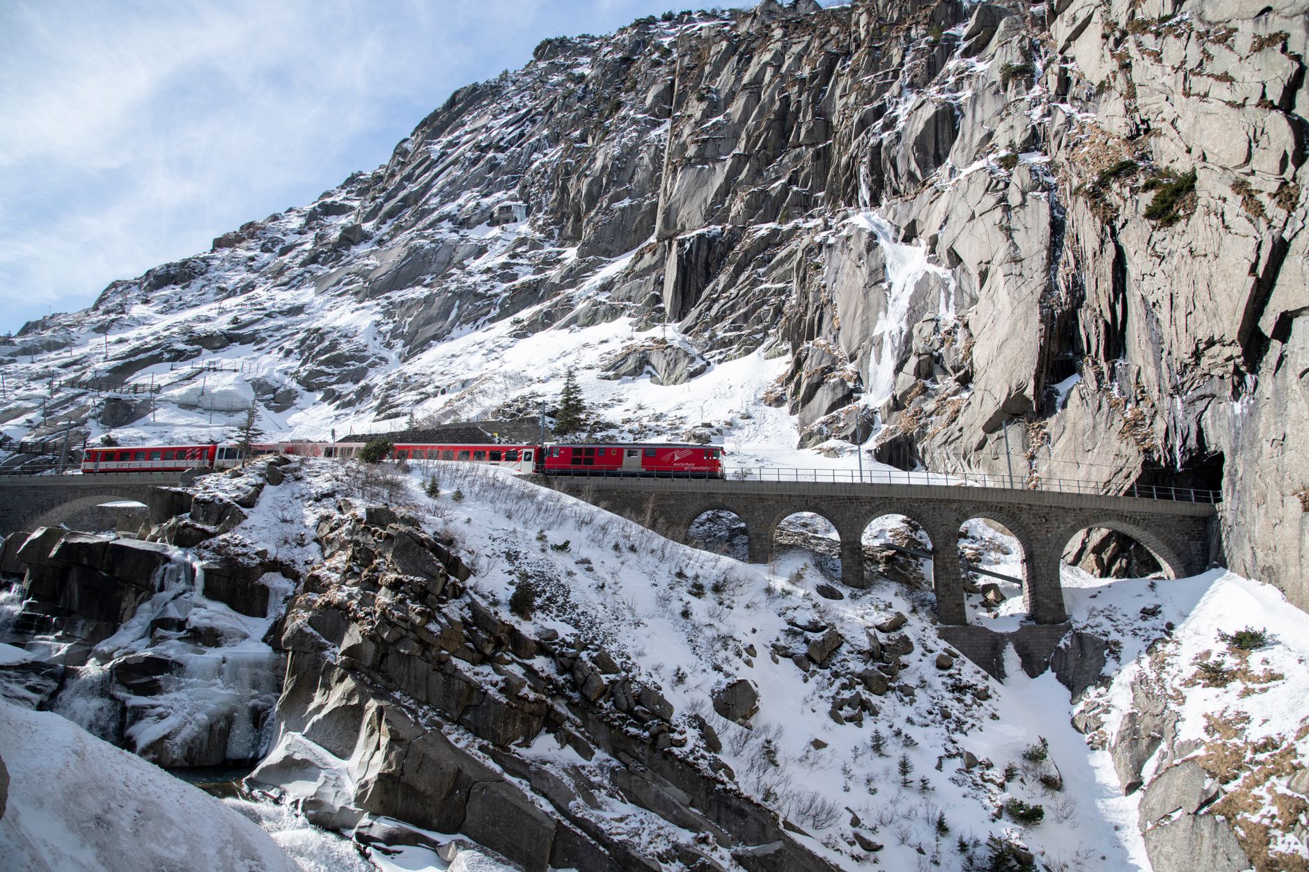 A vintage train winds through a stunning mountainous landscape under a clear sky, showcasing the romance and adventure of rail travel.