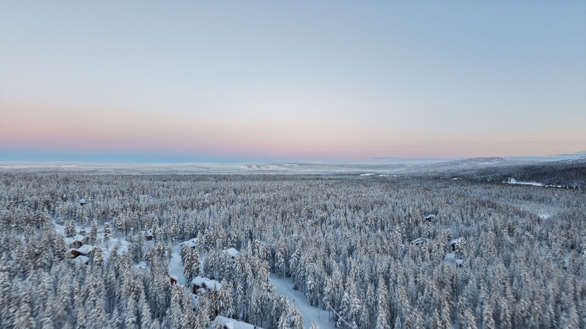 Sweeping aerial view of a pristine Finnish forest with a clear lake reflecting the sky, showcasing Finland's untouched natural beauty.