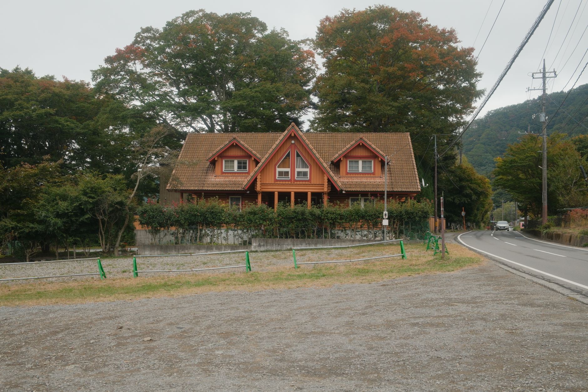 A breathtaking panoramic view of a traditional Japanese village nestled in a valley, surrounded by vibrant autumn forests and distant mountains shrouded in mist.