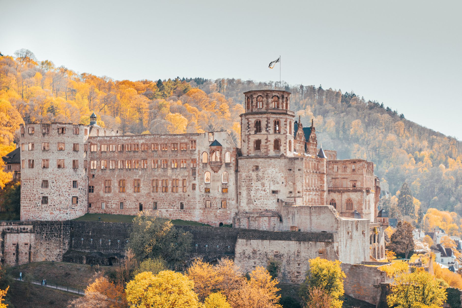 A sweeping panoramic view of a picturesque, less-traveled European village nestled in a valley, with ancient architecture and rolling hills under a soft, golden light, hinting at hidden stories.