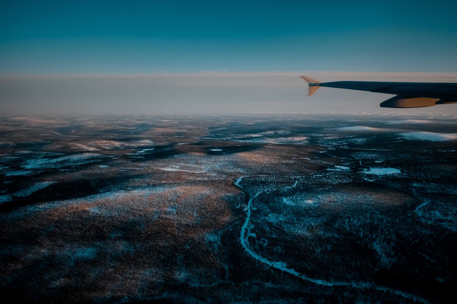 Sweeping aerial view of Finland's vast, serene wilderness with ancient forests and countless lakes under a clear sky.