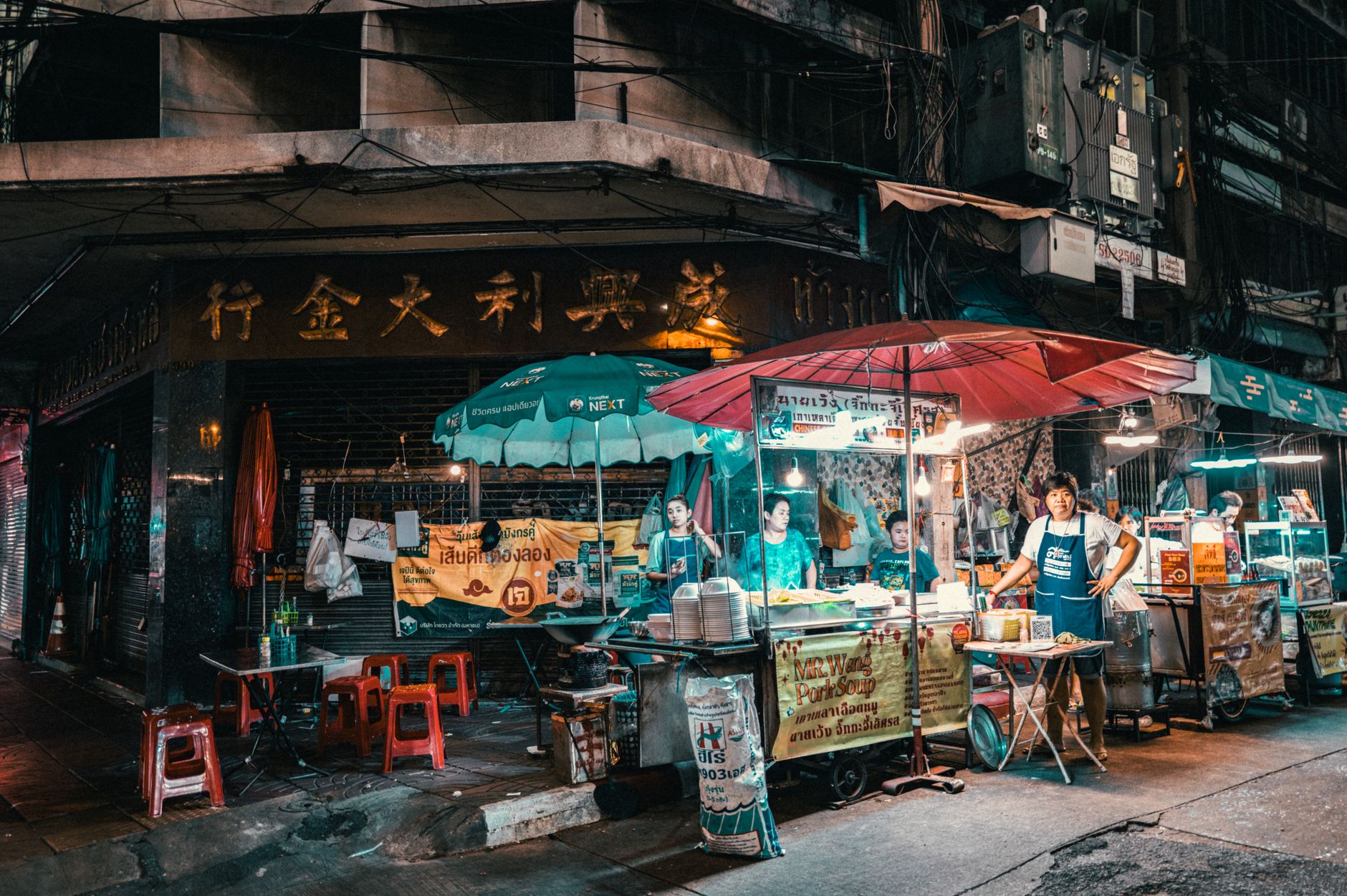 A vibrant, bustling street food market scene with diverse stalls and people enjoying various international dishes under string lights.