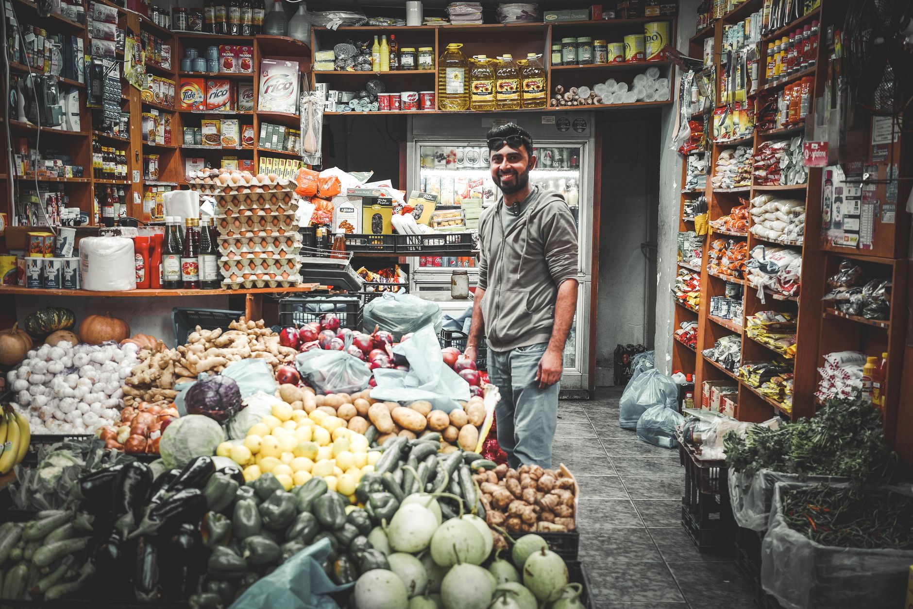 Busy street market in Athens, Greece, with people browsing food stalls and historic buildings in the background.