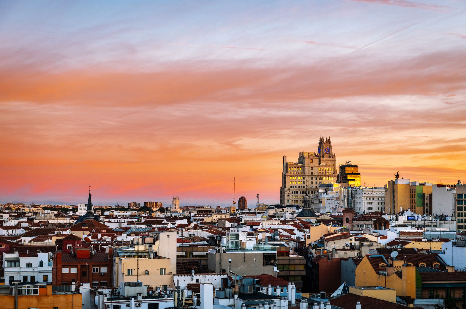 A sweeping view of Madrid's historic rooftops at sunset, with a bustling street market below, evoking the city's vibrant culinary scene.