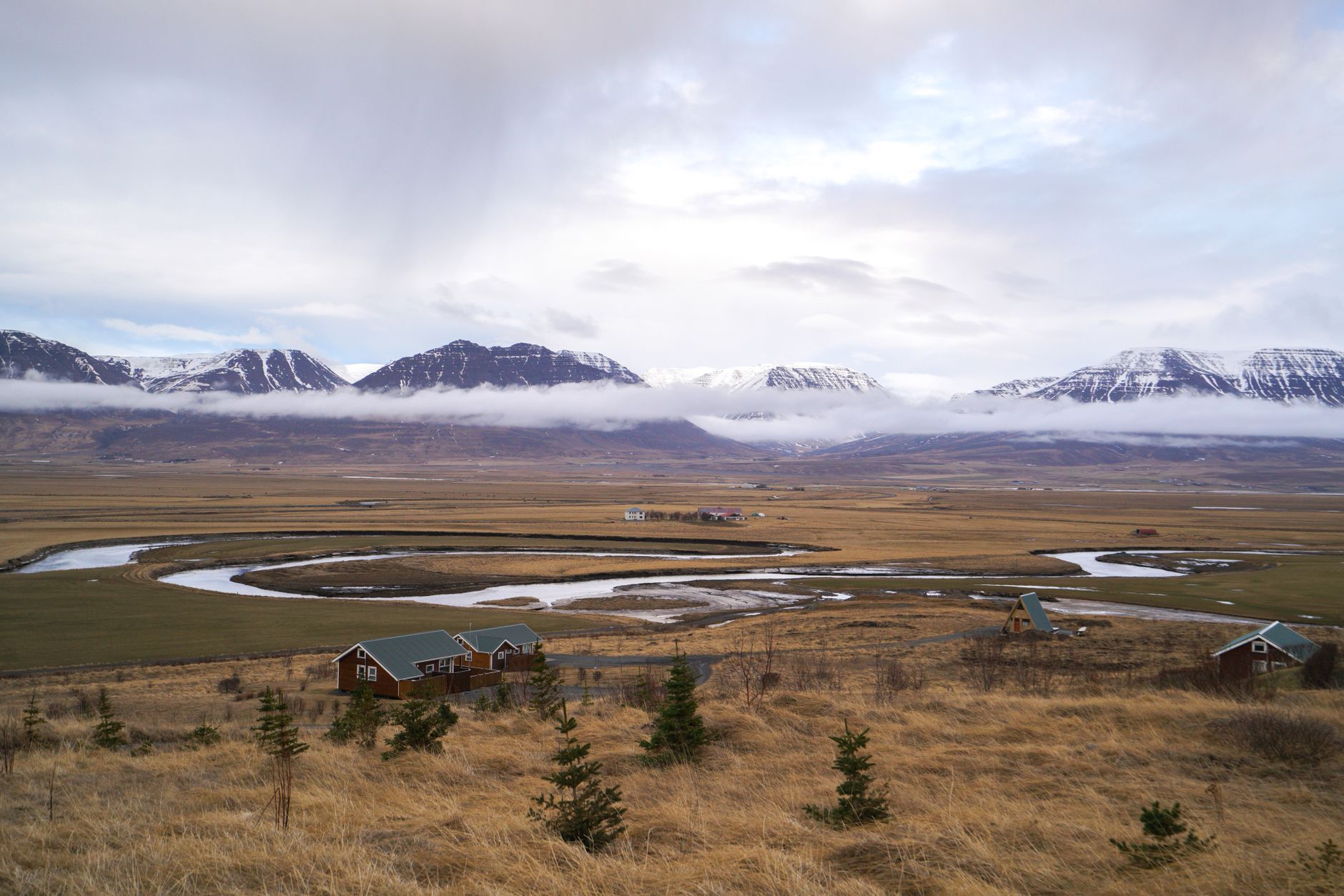 A lone person stands on a high ridge overlooking a vast, untouched natural landscape of mountains and valleys under a dramatic sky, evoking a sense of deep connection to the earth.