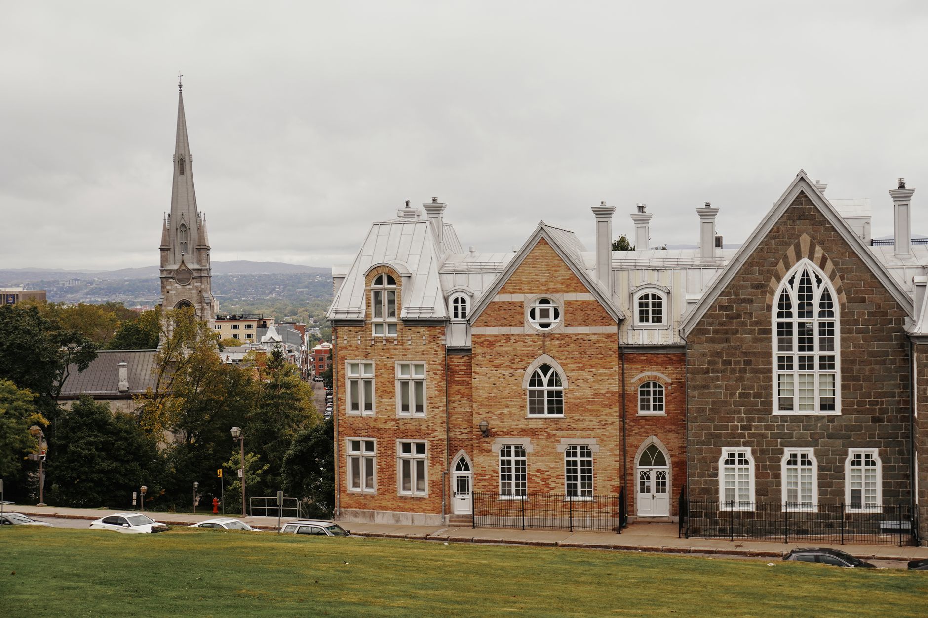 A picturesque small town in rural Quebec with traditional architecture, surrounded by lush autumn foliage and a serene river.
