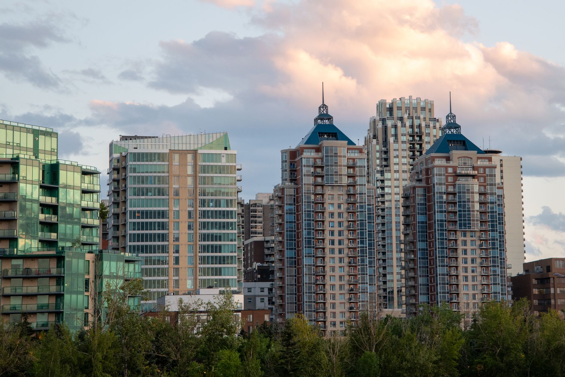 A split image showing the modern Calgary skyline against a vast prairie landscape, and the historic colorful buildings with external staircases of Montreal's Plateau.