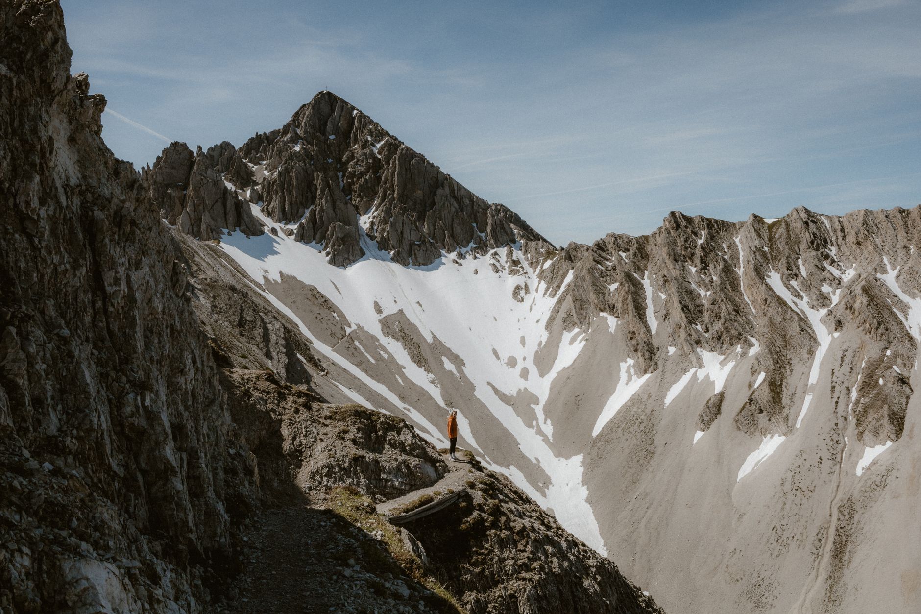 A lone figure stands on a cliff overlooking a vast, serene landscape, suggesting quiet exploration and discovery.