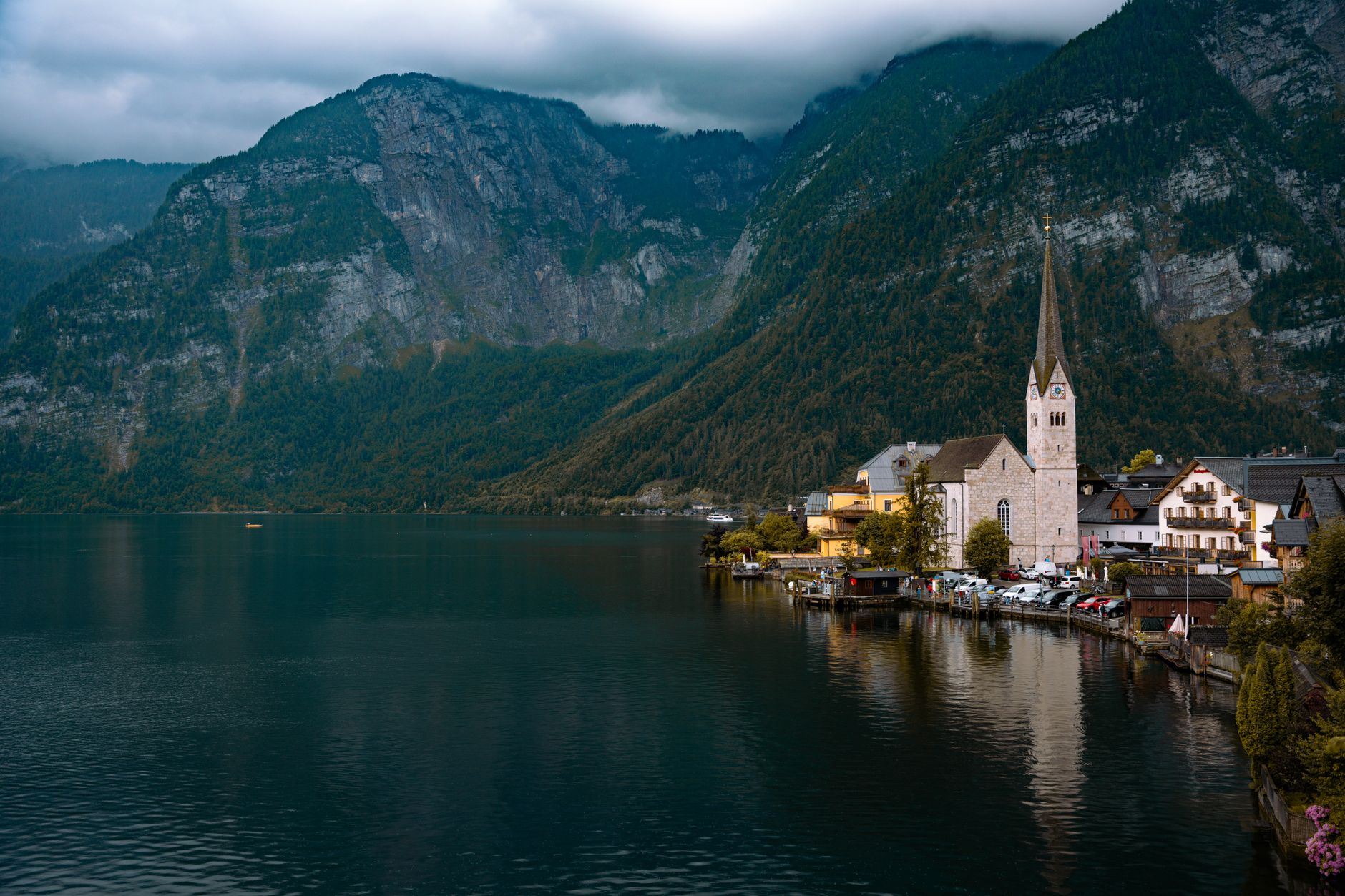 A sweeping, dramatic landscape featuring mountains, a winding road, and a distant village, evoking the mystery of undiscovered travel destinations.