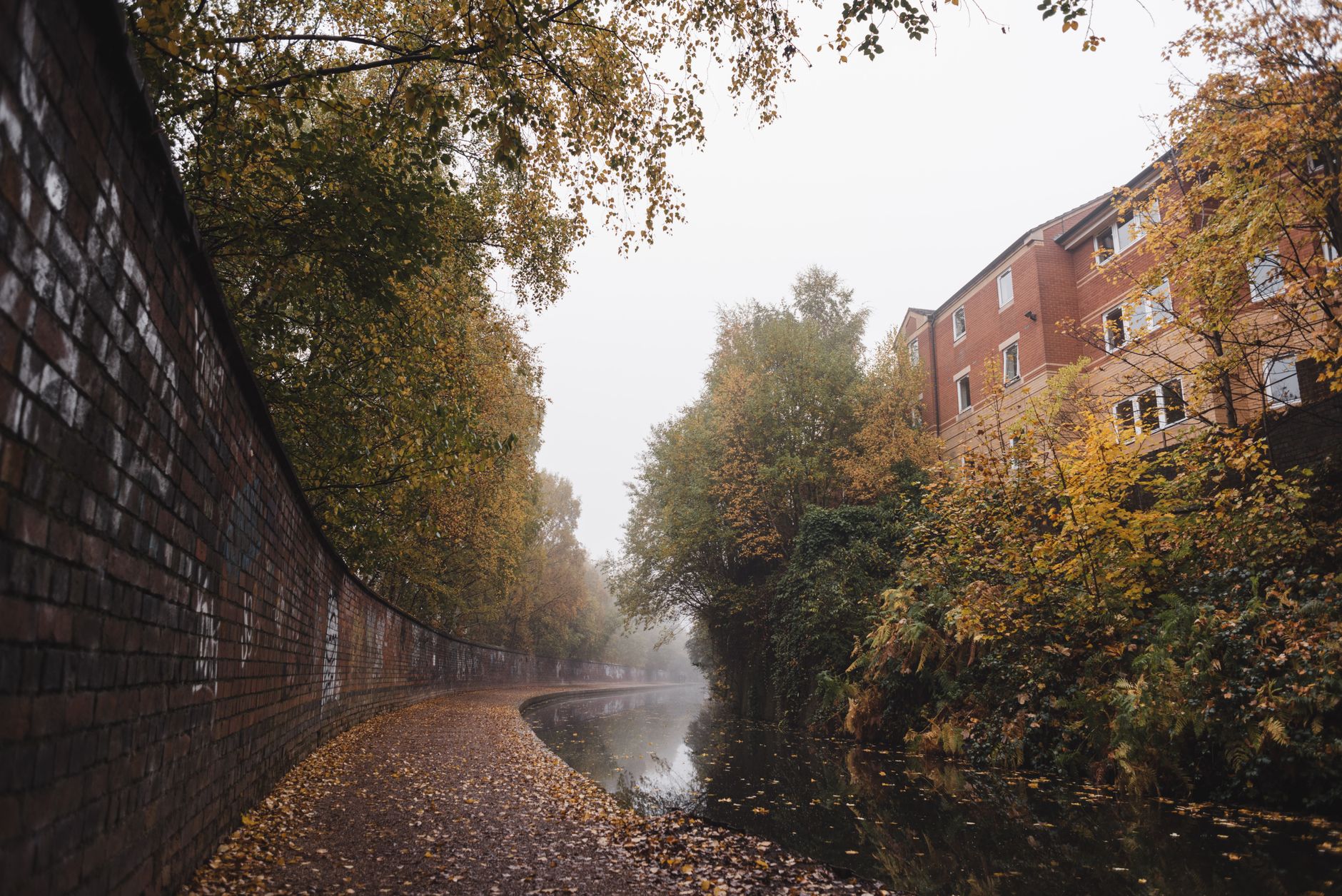 A serene view of a historic Birmingham canal, with reflections of old brick buildings and a narrowboat, capturing the city's hidden charm.